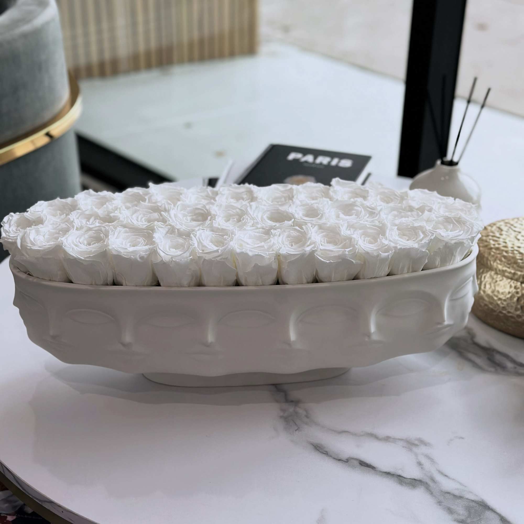 White roses arranged in a low oval ceramic vase