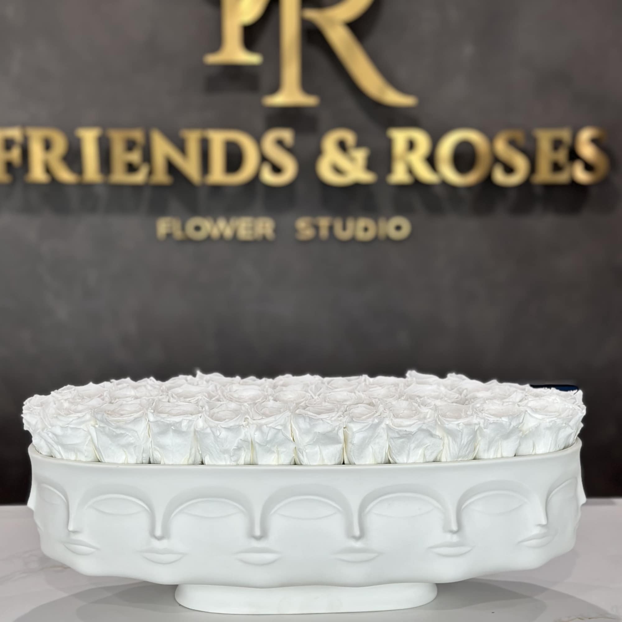 White roses arranged in a low oval white vase