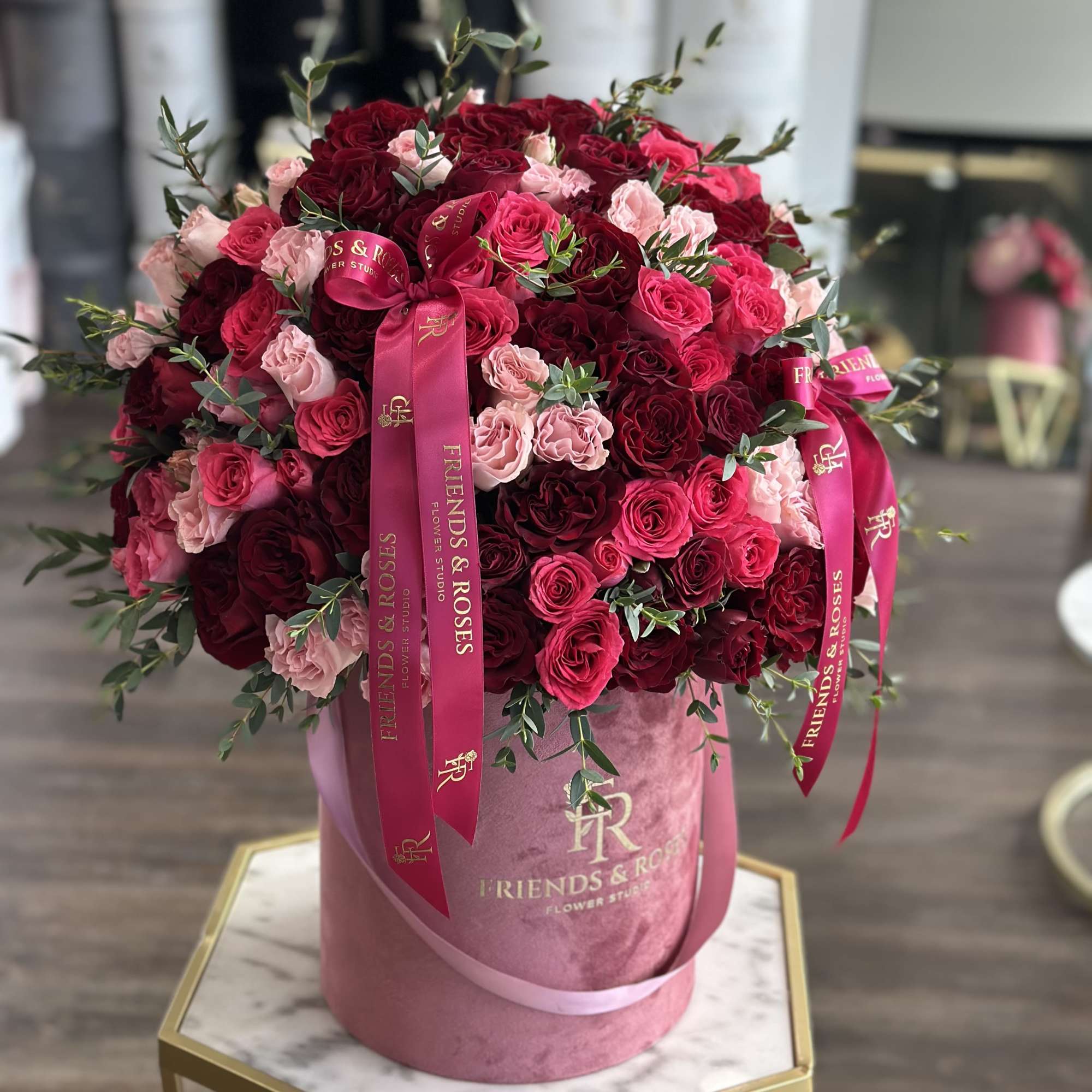 Large bouquet of red and pink roses in a pink hat box with ribbons
