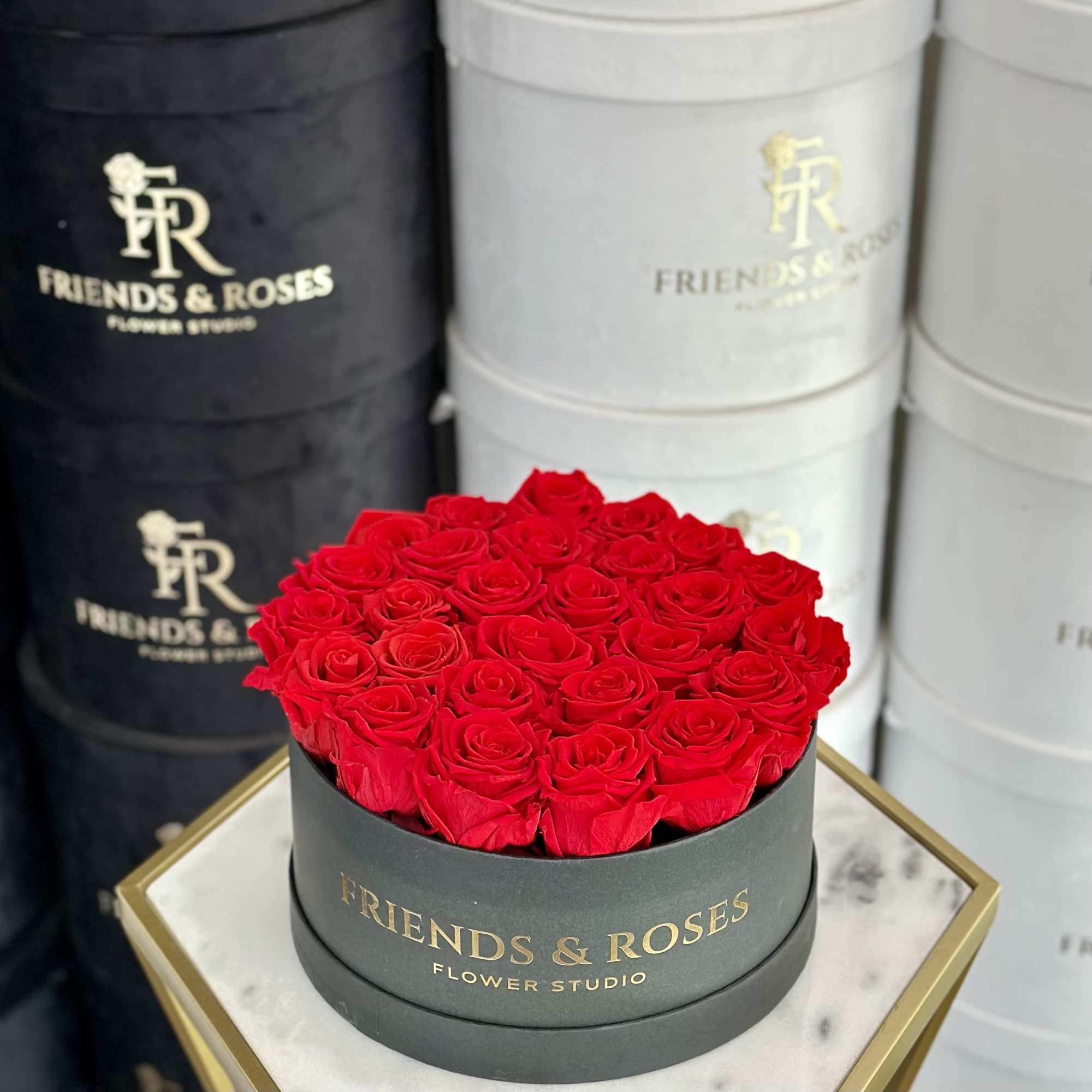 Round box filled with red roses on a marble-topped stand
