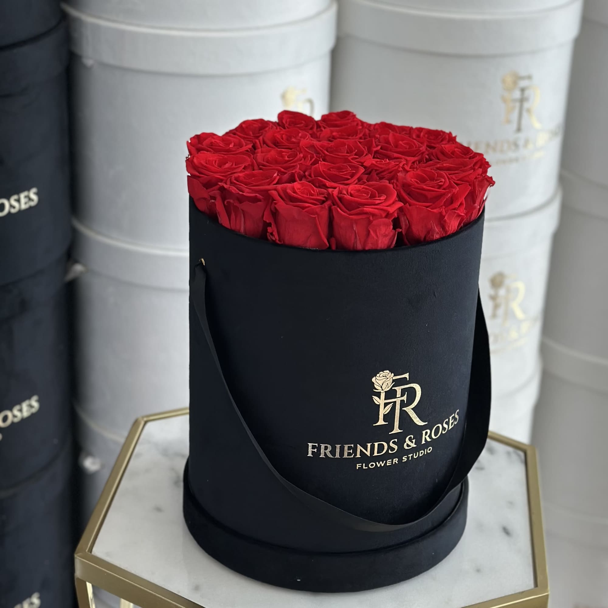Red roses arranged in a black round hat box