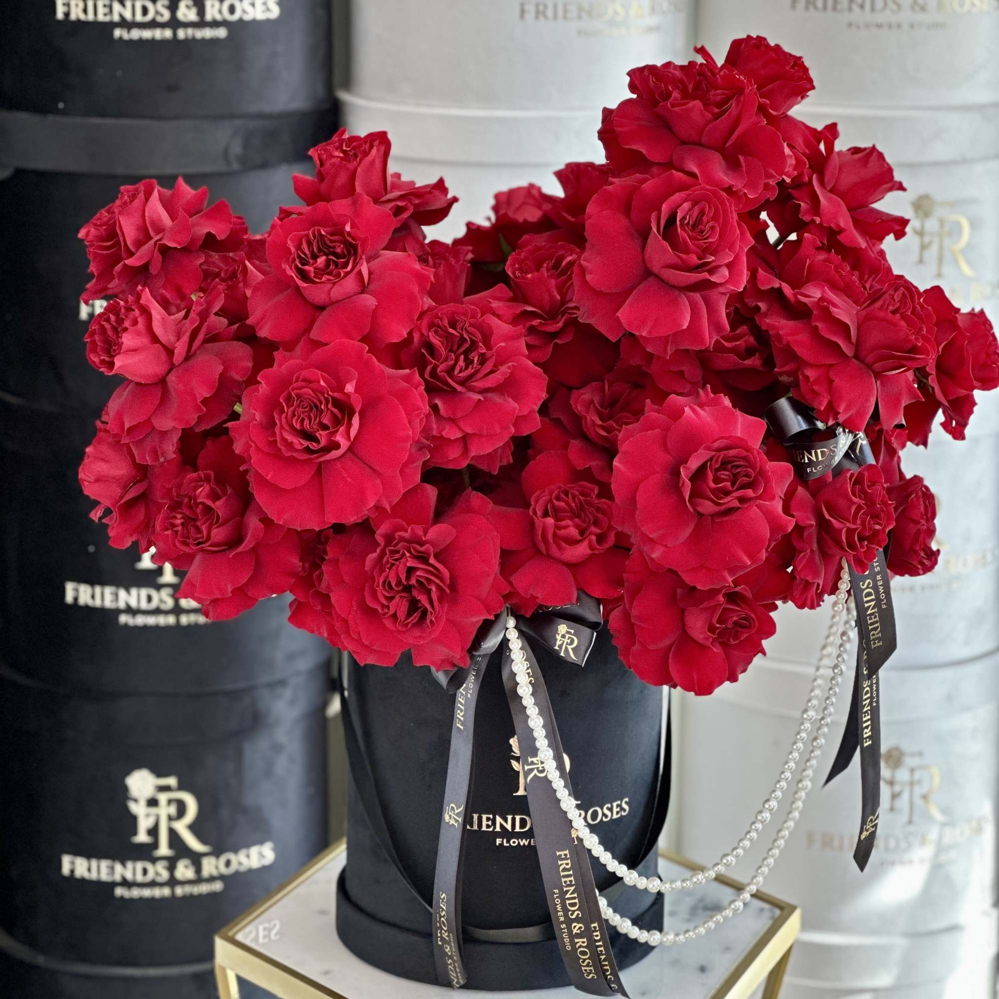Red rose bouquet in a black hatbox with ribbon and pearl strands