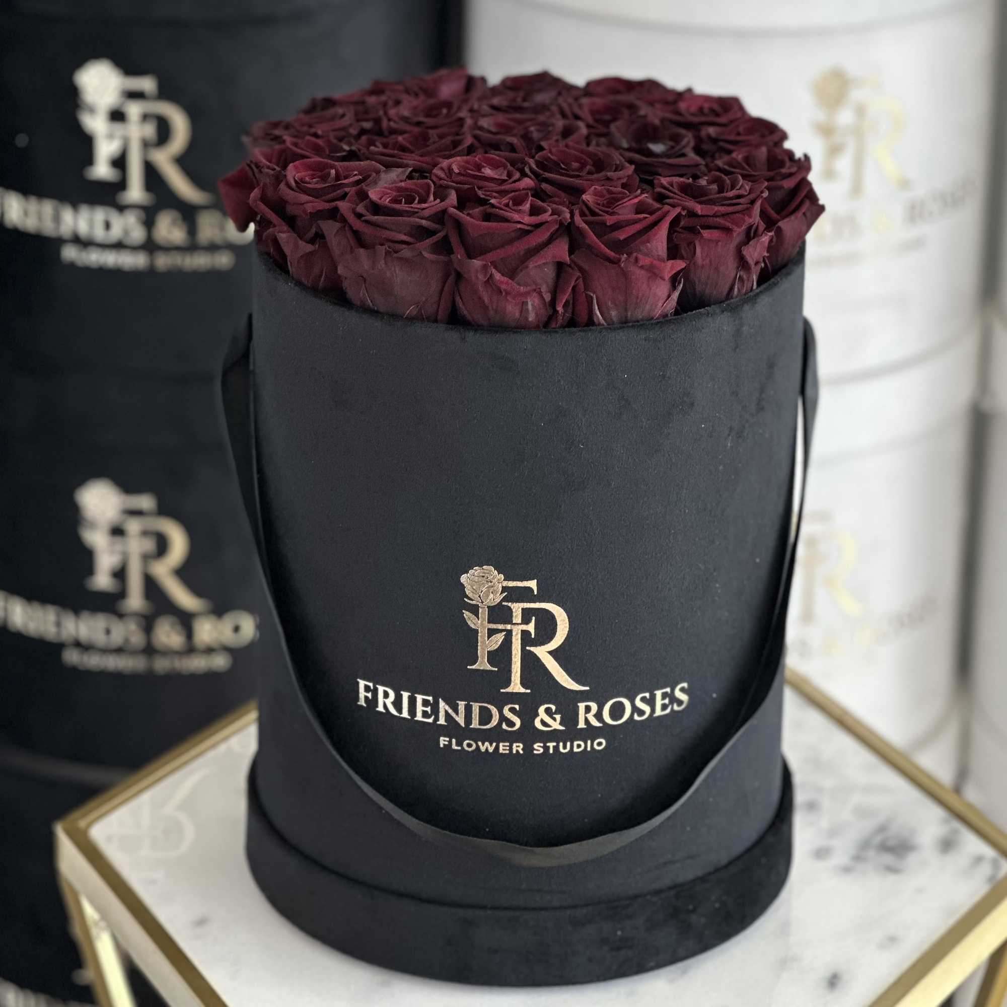 Box of deep burgundy roses in a black round hatbox