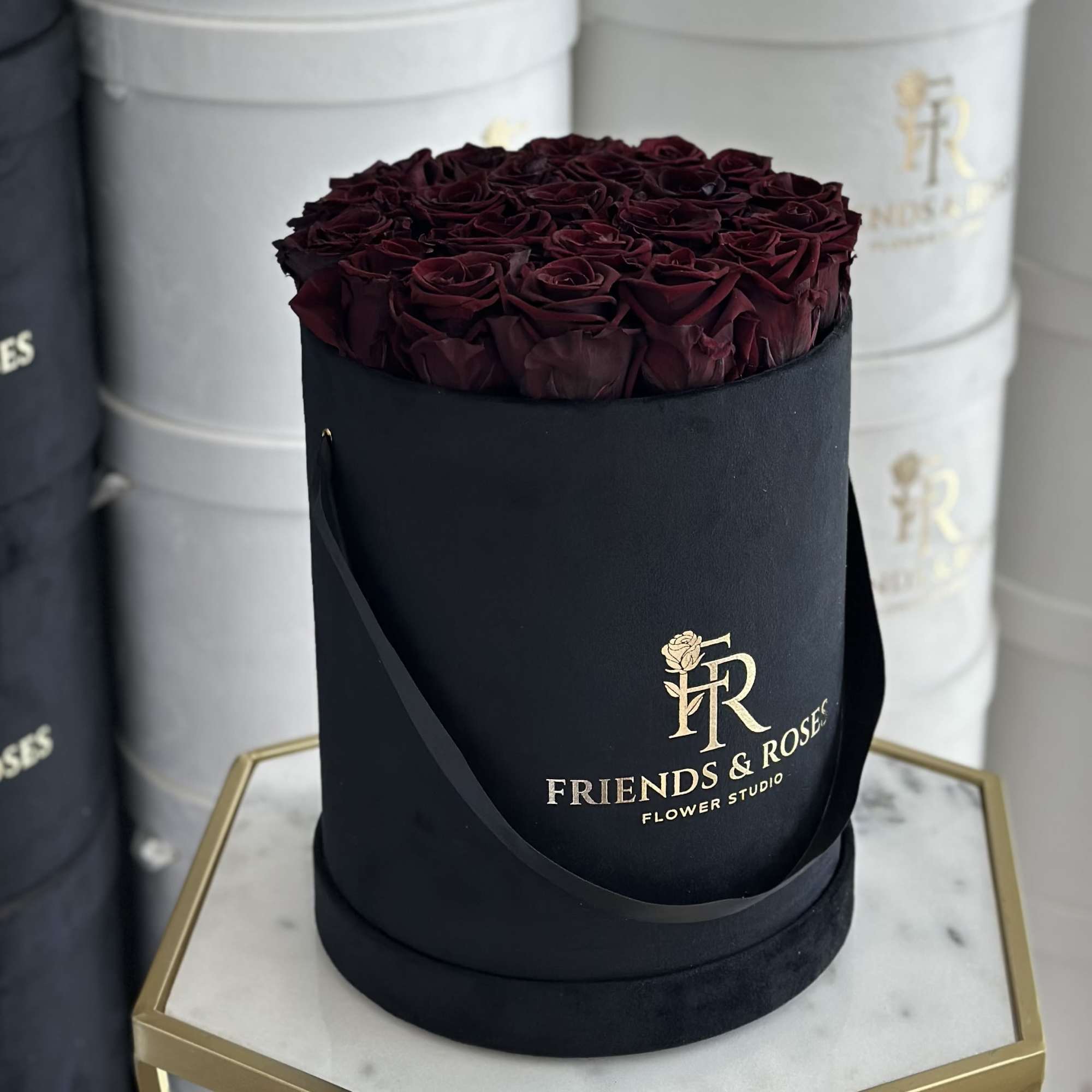 Dark red roses arranged in a black round hat box