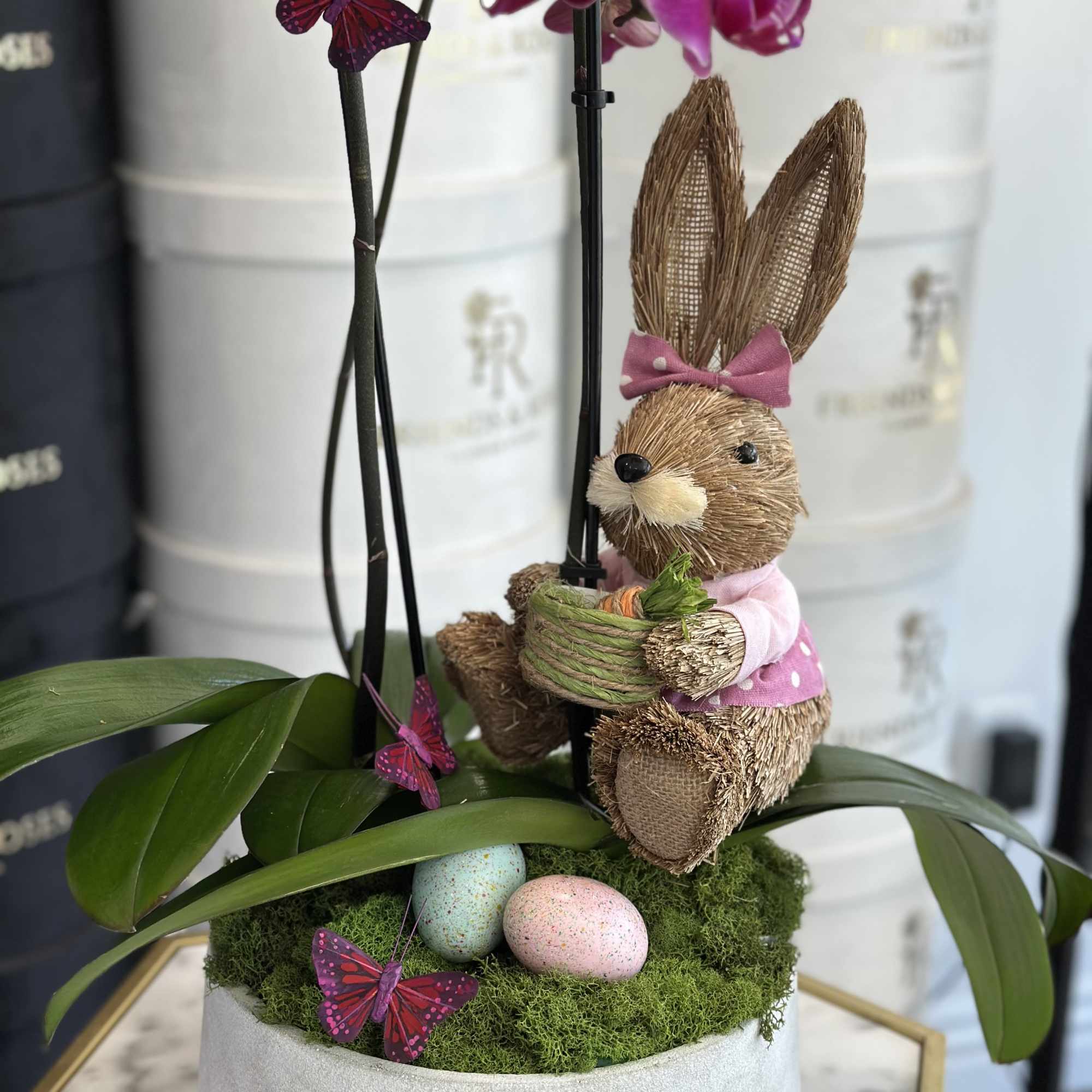 Potted orchid with a straw bunny, moss, and pastel eggs