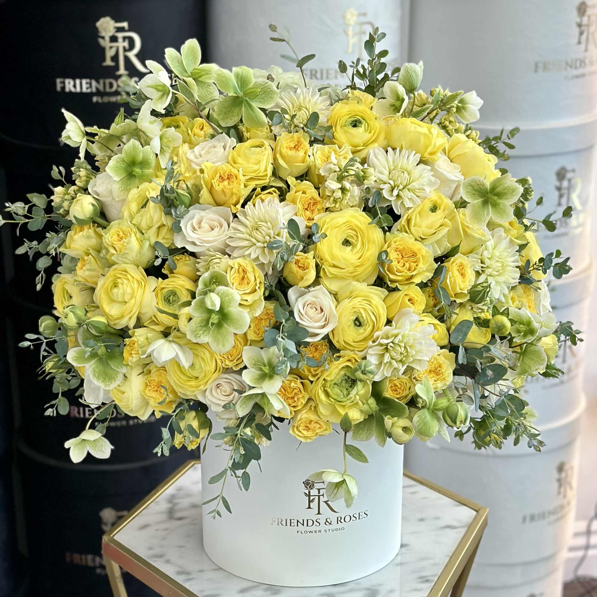 Yellow and white floral arrangement in a white hat box