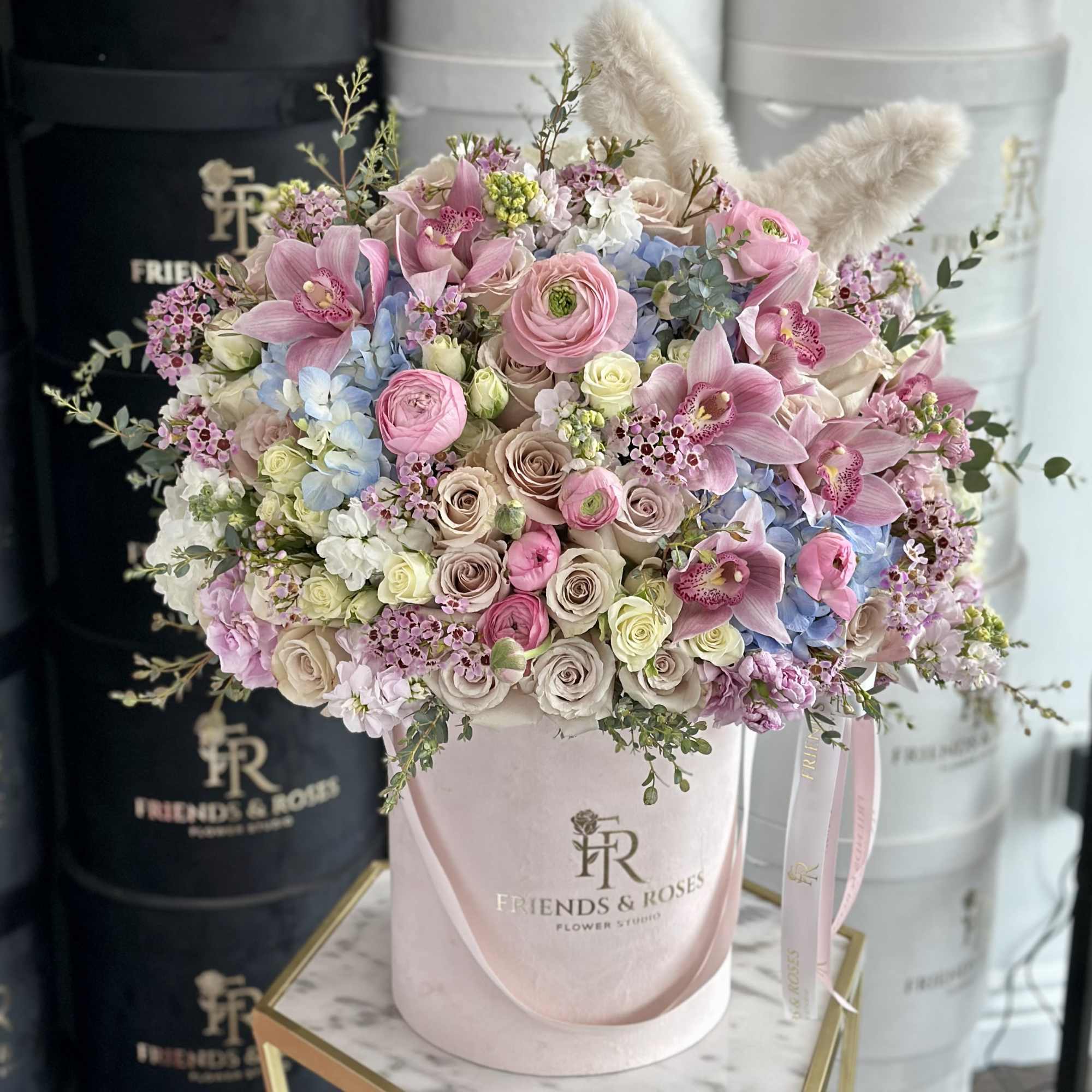 Pink and blue mixed flower bouquet in a pale pink hatbox
