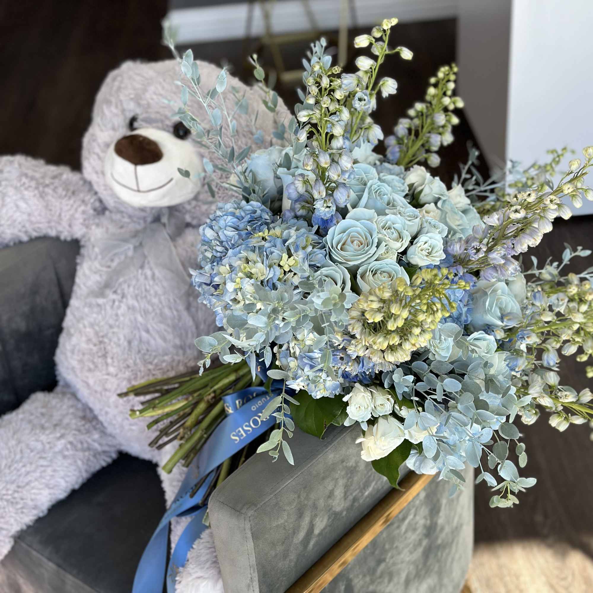 Blue and white bouquet beside a gray teddy bear