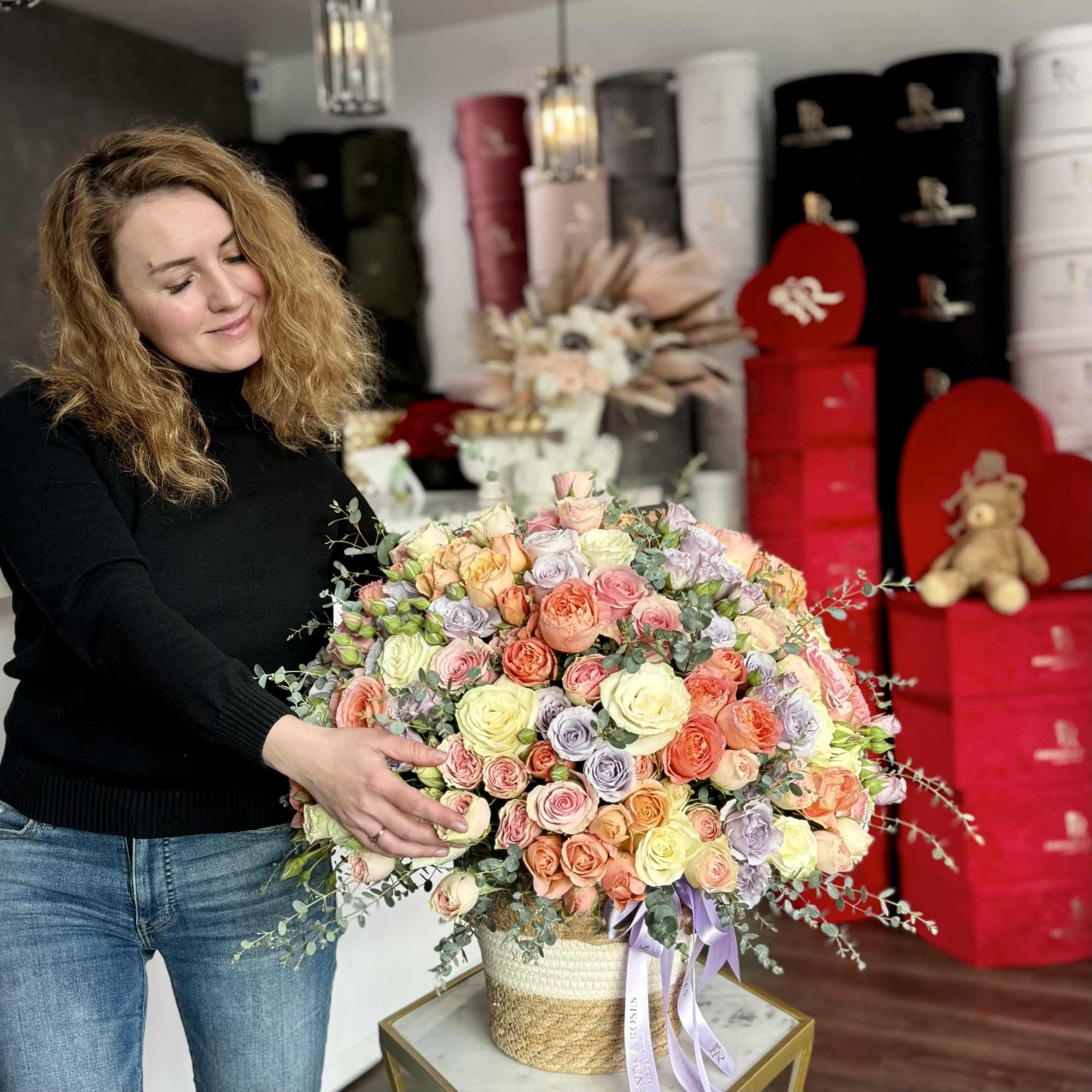 Woman holding a large pastel rose arrangement in a woven basket