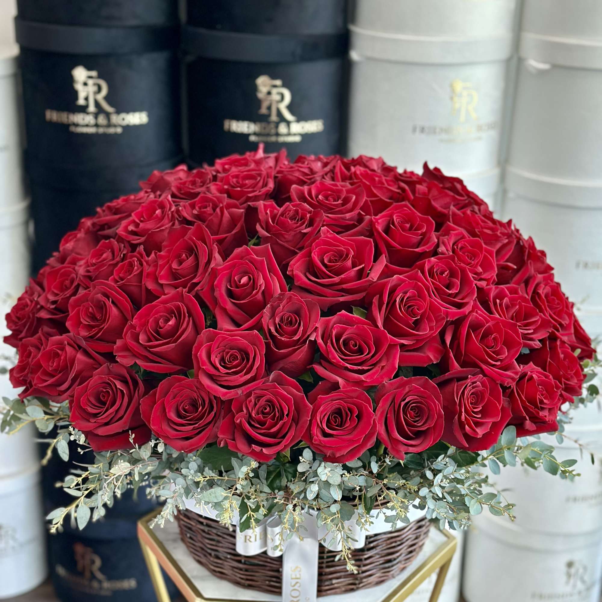 Large bouquet of red roses in a wicker basket with eucalyptus accents