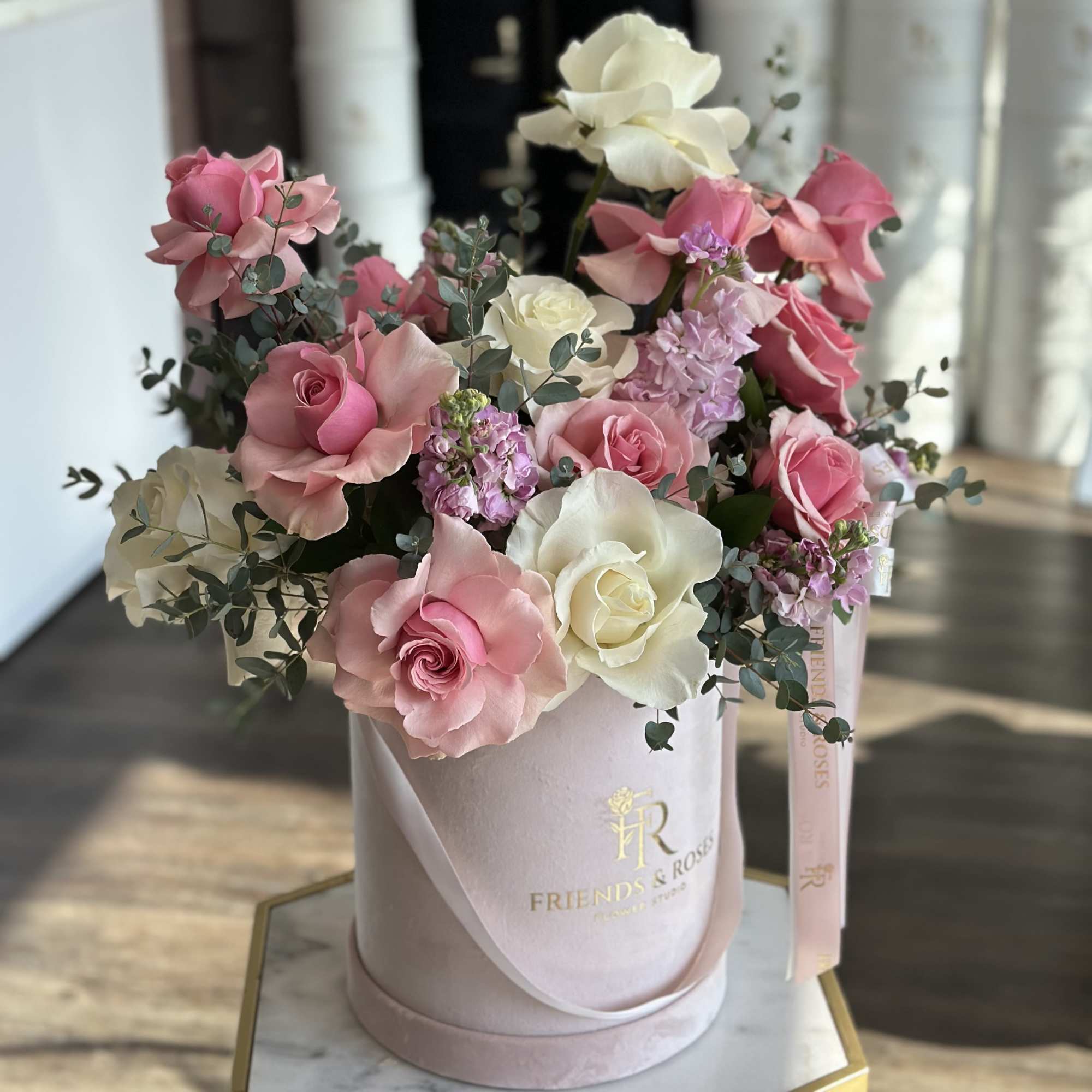 Pink and white roses arranged in a round hatbox