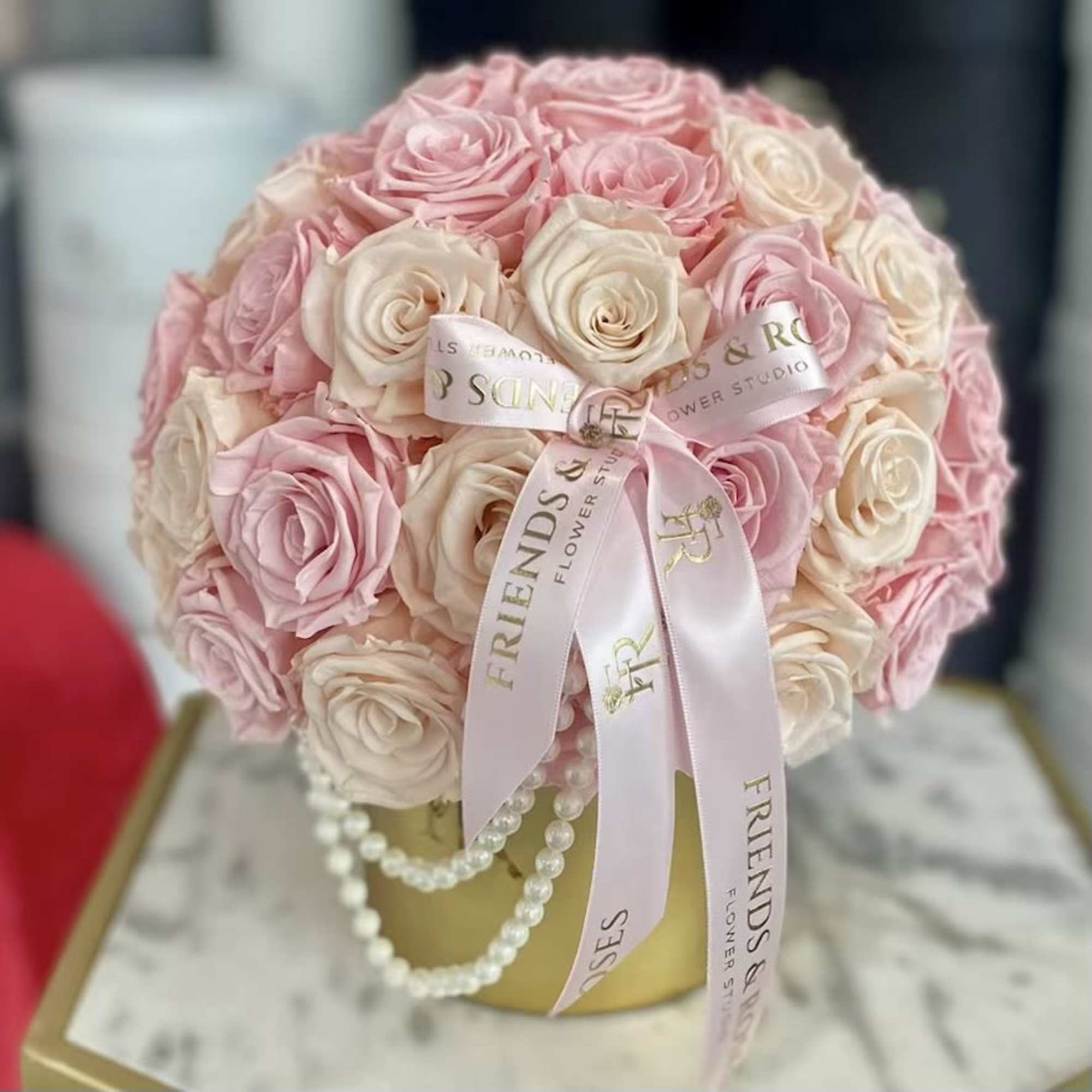 Round bouquet of pink and cream roses with a ribbon and pearl strands