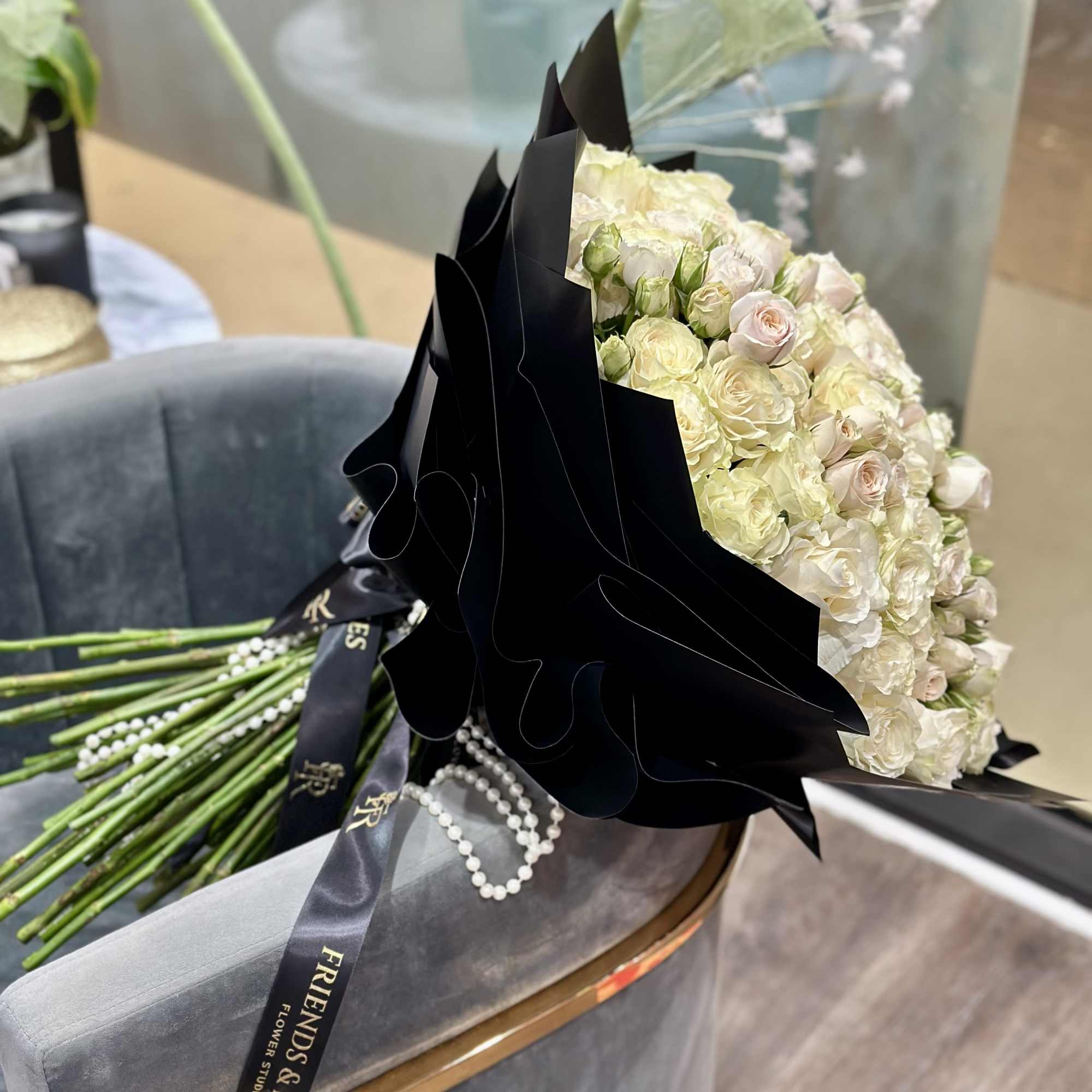 Large bouquet of pale cream and blush roses wrapped in black paper