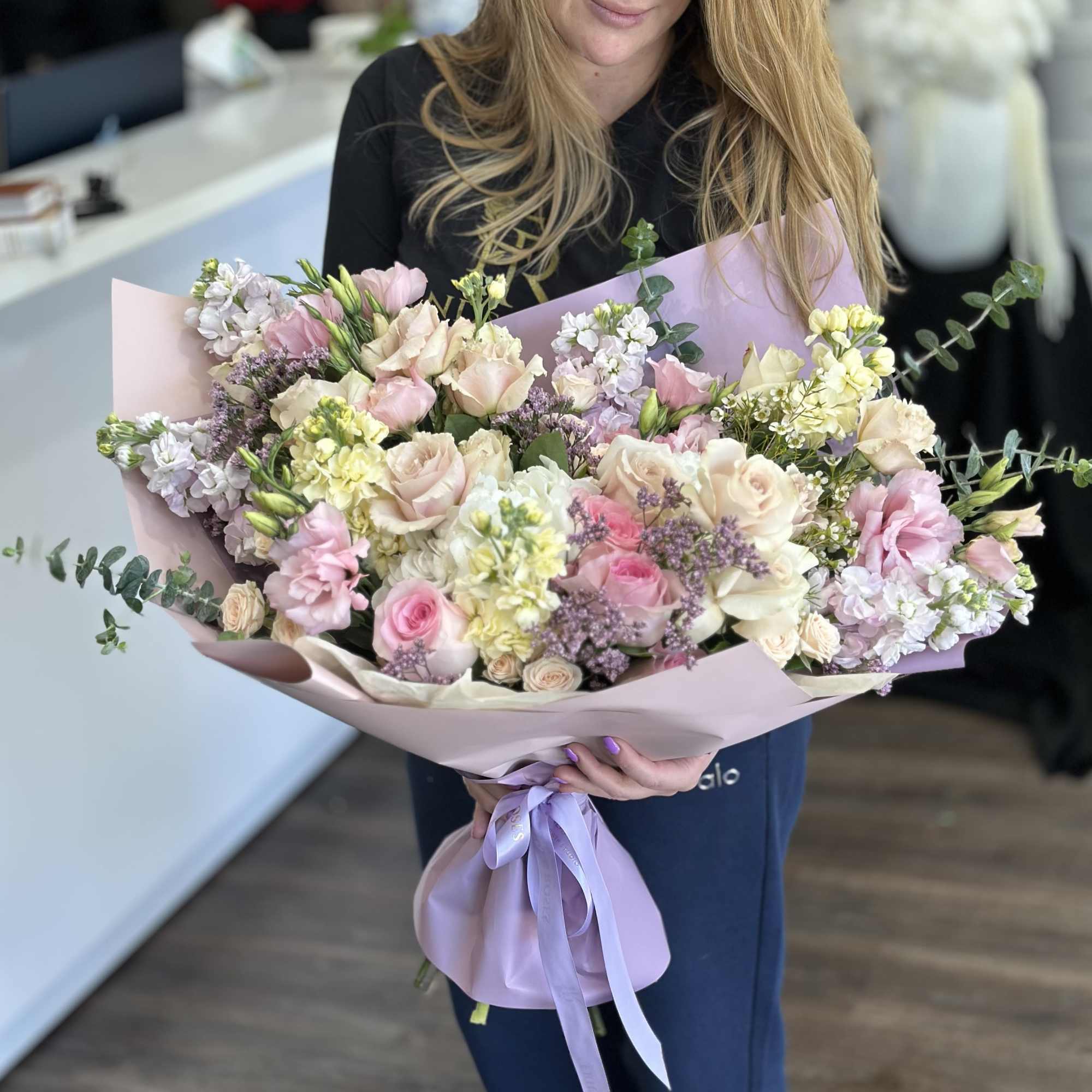 Large pastel bouquet of pink and cream flowers wrapped in lavender paper