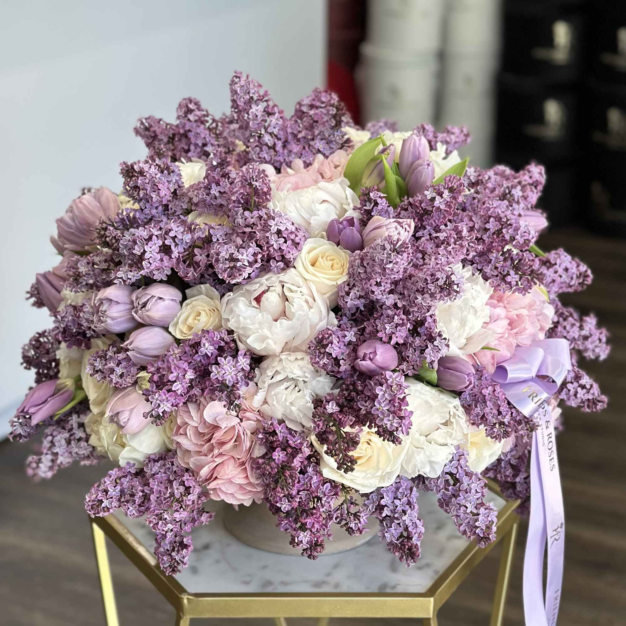 Lavender and white bouquet in a round vase with a ribbon