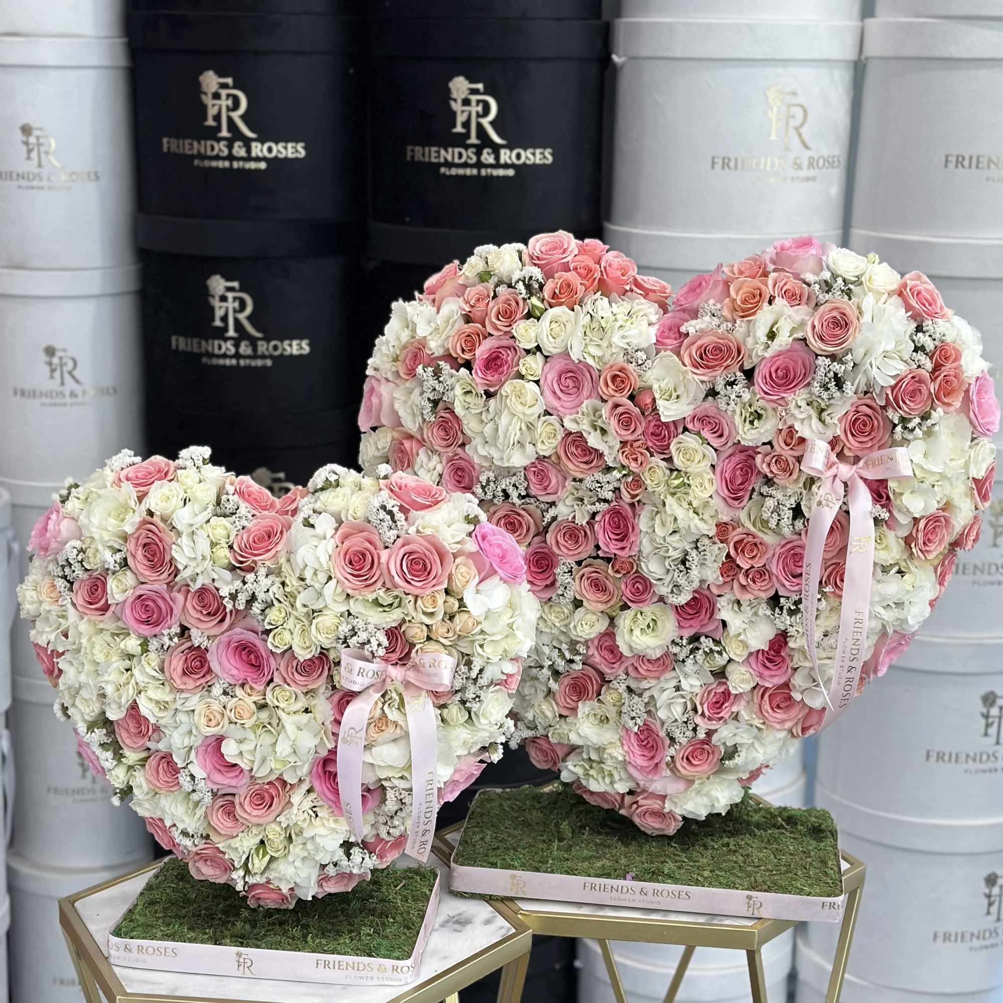 Two heart-shaped pink and white rose arrangements on stands