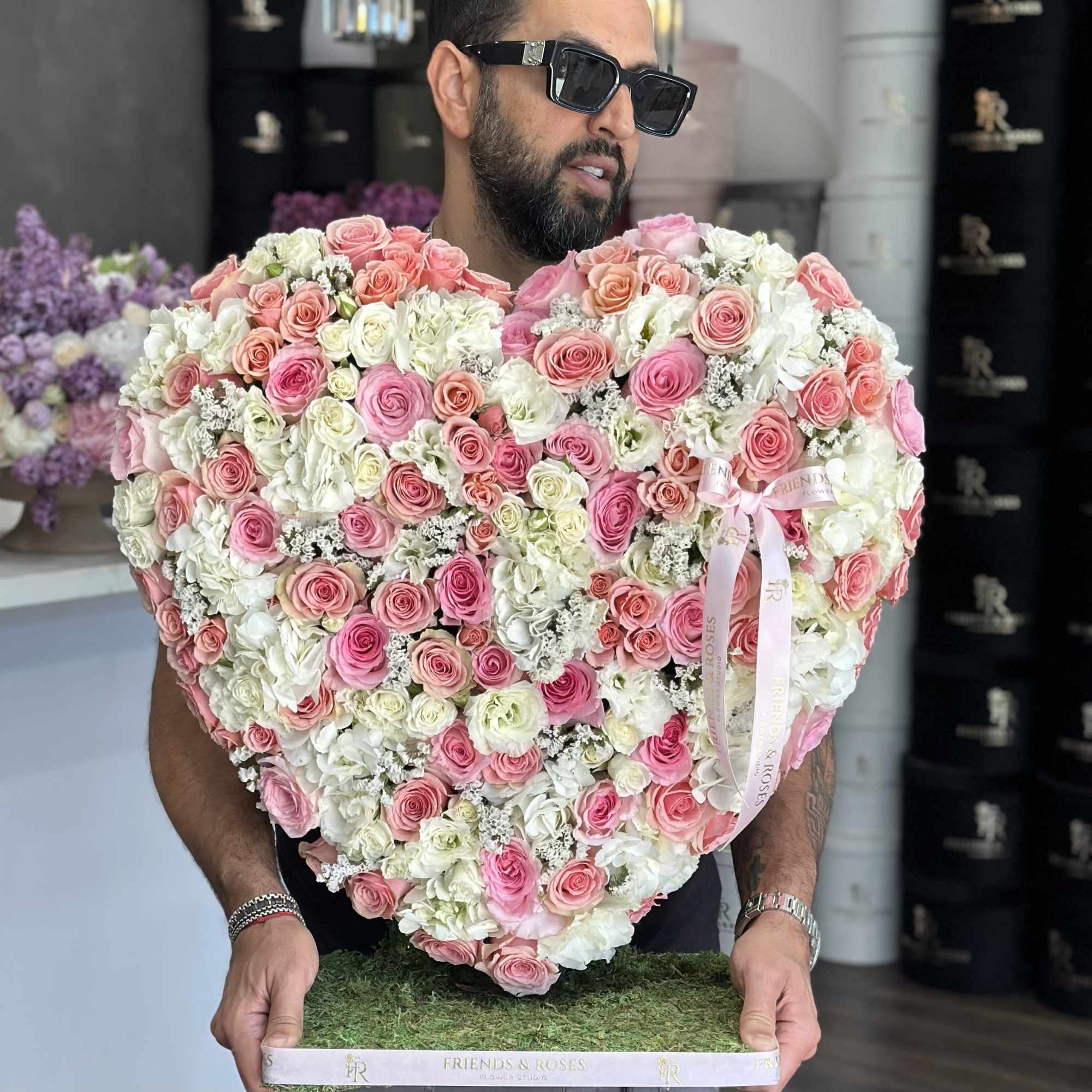 Heart-shaped bouquet of pink and white roses held by a man