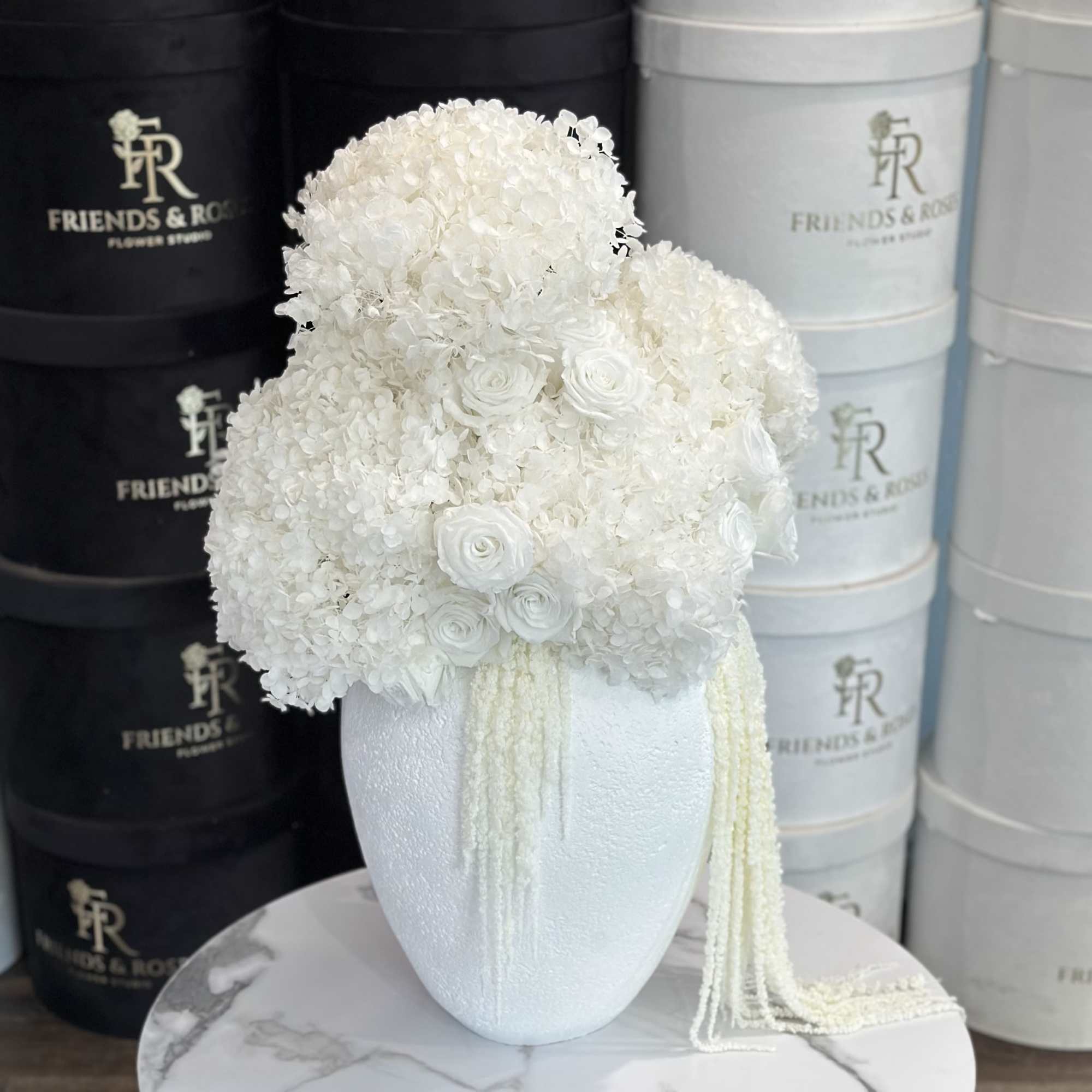White floral arrangement in a textured vase with trailing strands