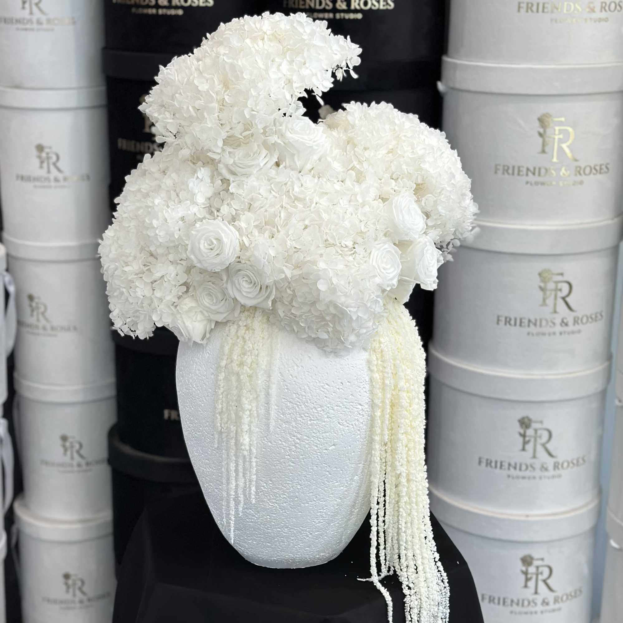 White floral arrangement in a textured white vase with trailing strands.