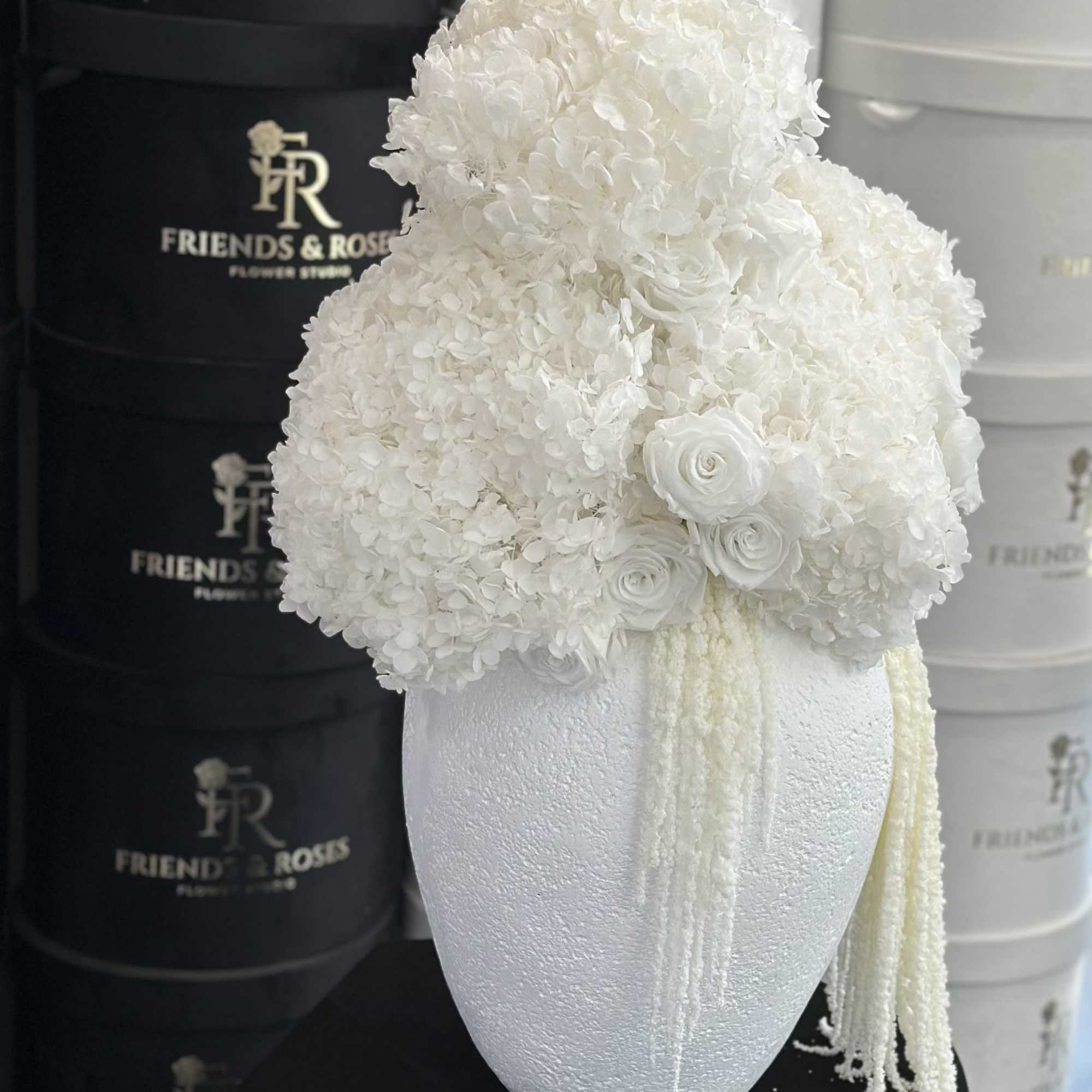 White floral arrangement in a textured vase with trailing strands, photo 3 of 3