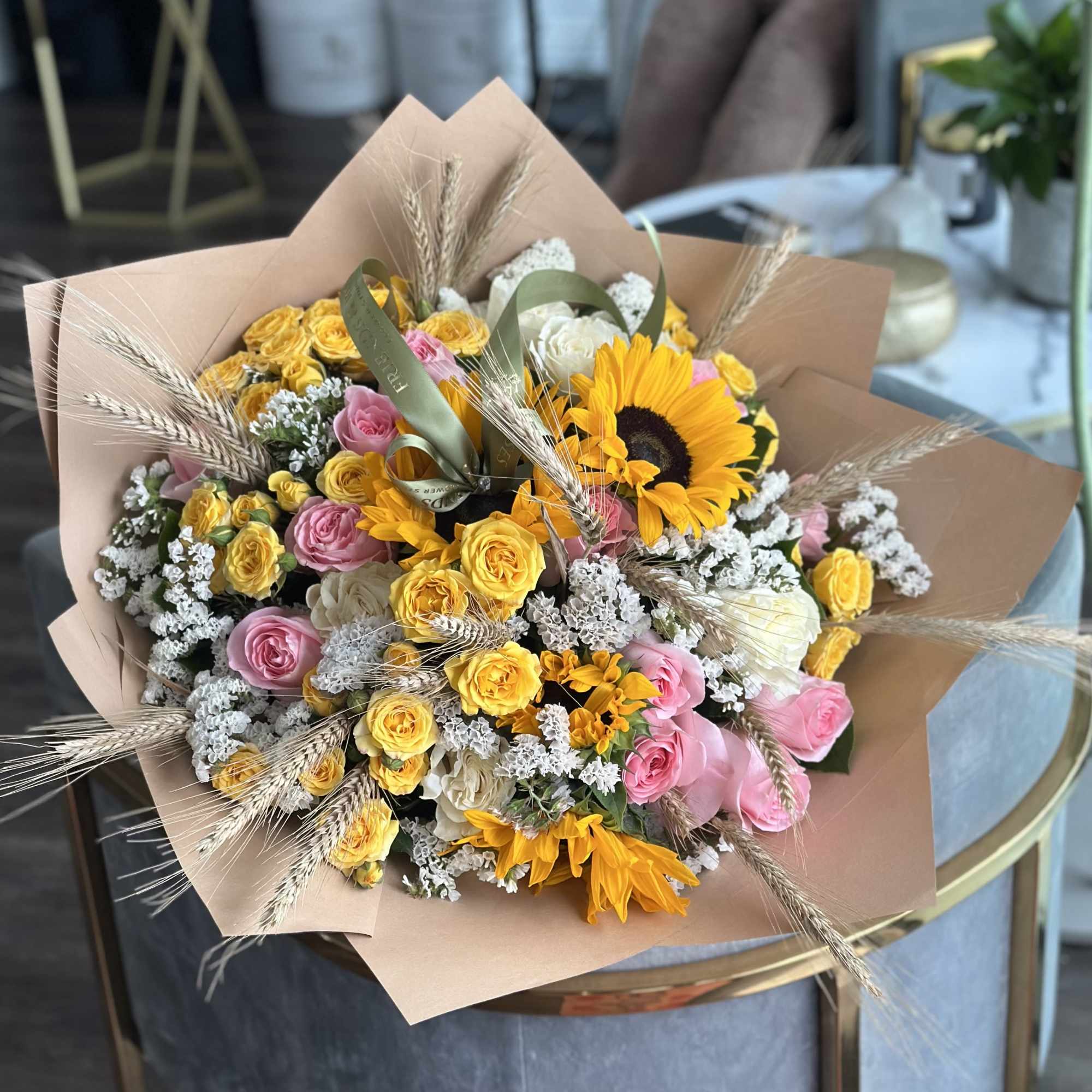 Bouquet of yellow and pink roses with sunflowers wrapped in tan paper