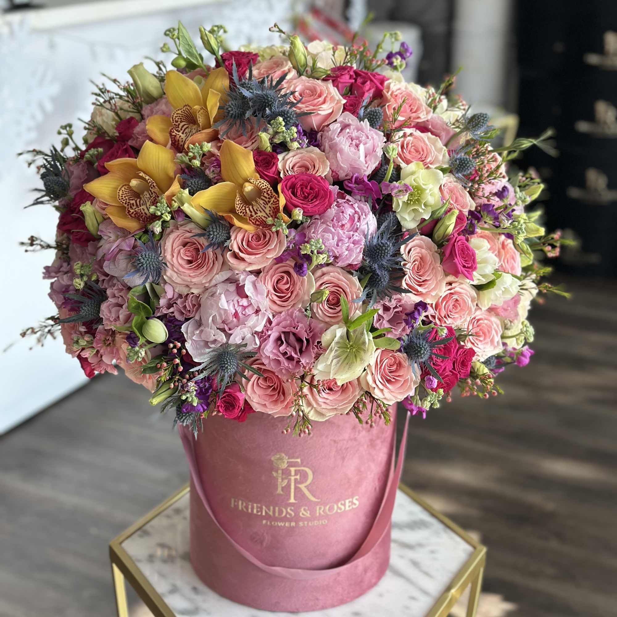 Large pink and yellow mixed flower arrangement in a pink hat box