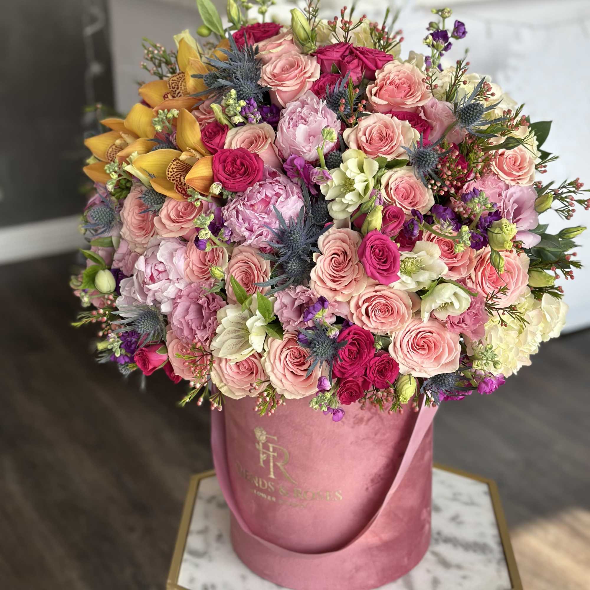 Large bouquet of pink and yellow flowers in a pink hatbox