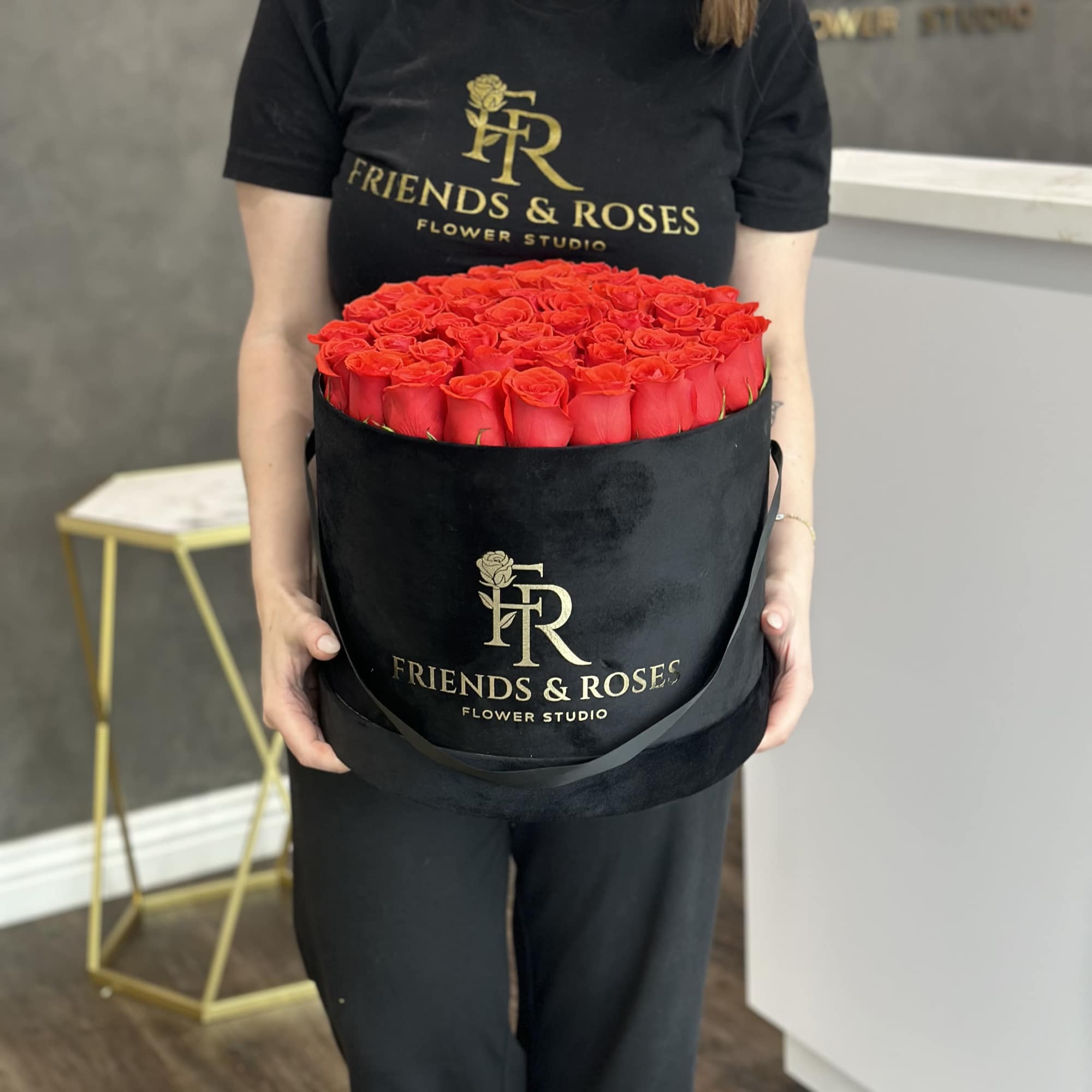 Large round box of red roses held by a person