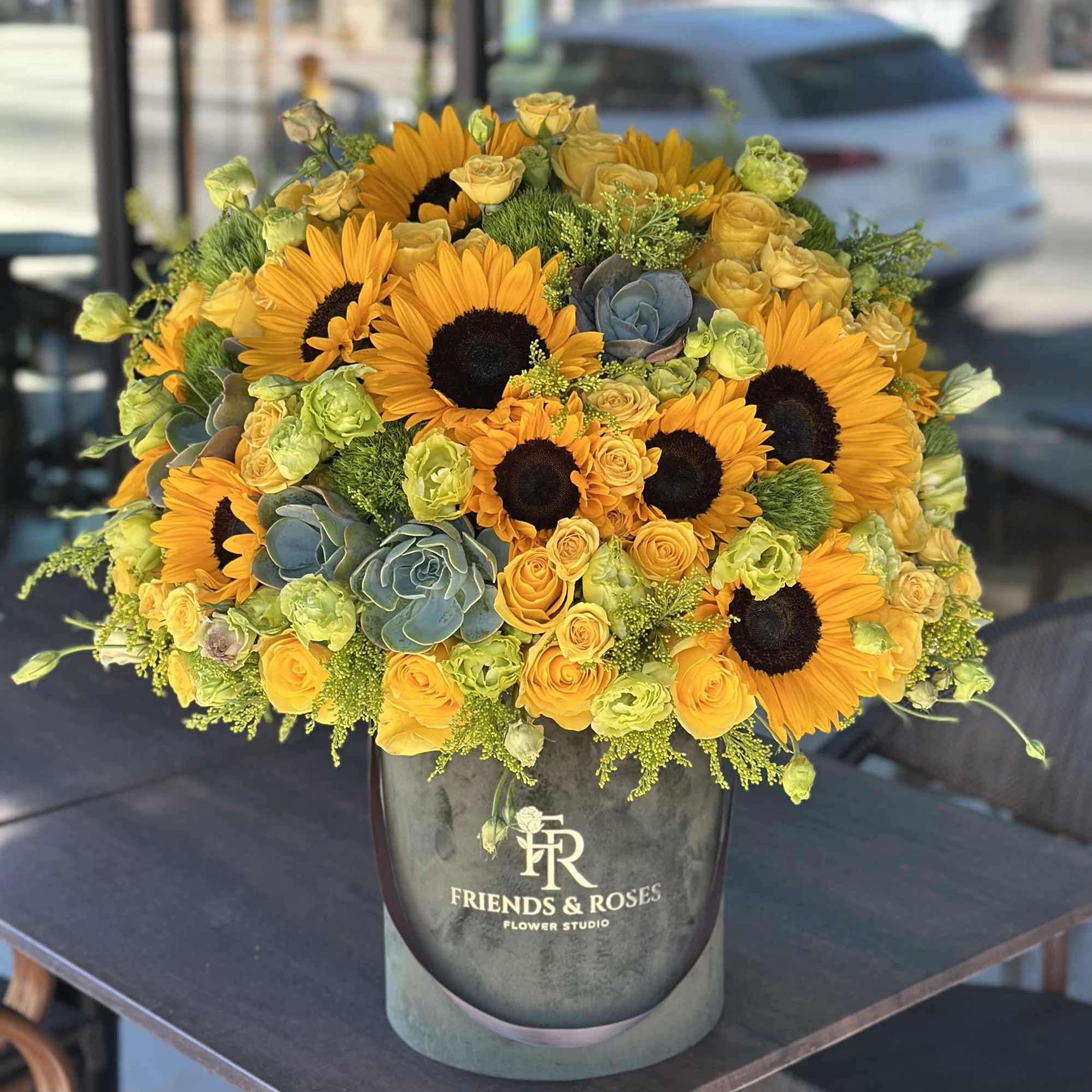 Yellow sunflowers and roses arranged in a gray vase