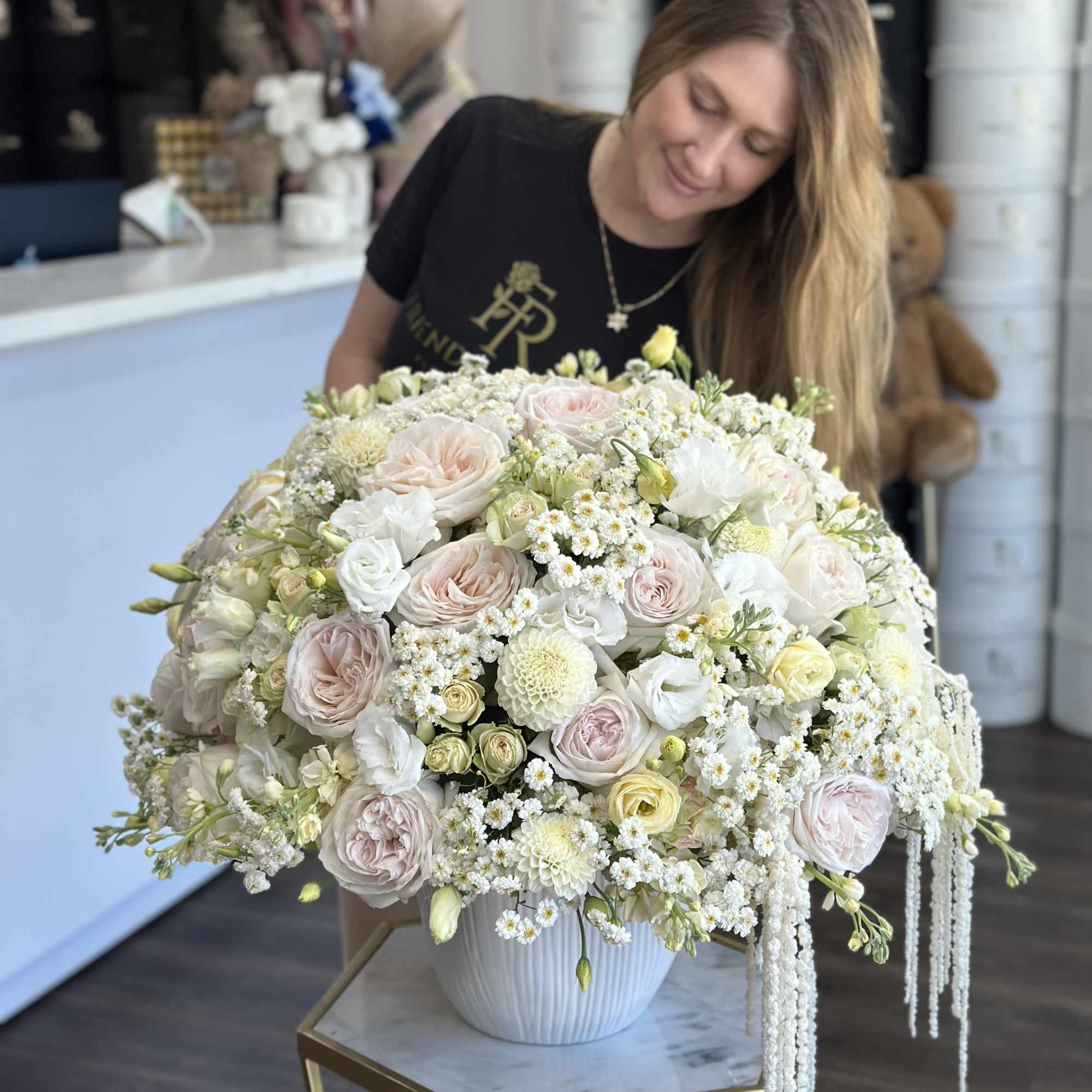 Large pastel floral arrangement in a white vase with roses and white blooms