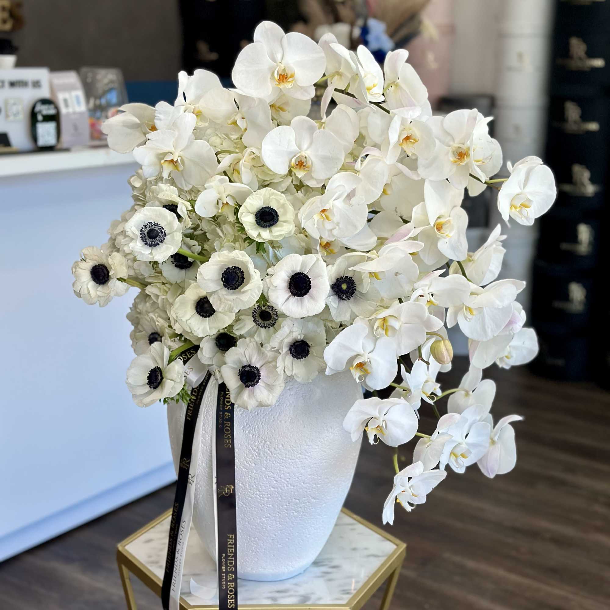 White orchids and white anemones arranged in a white vase
