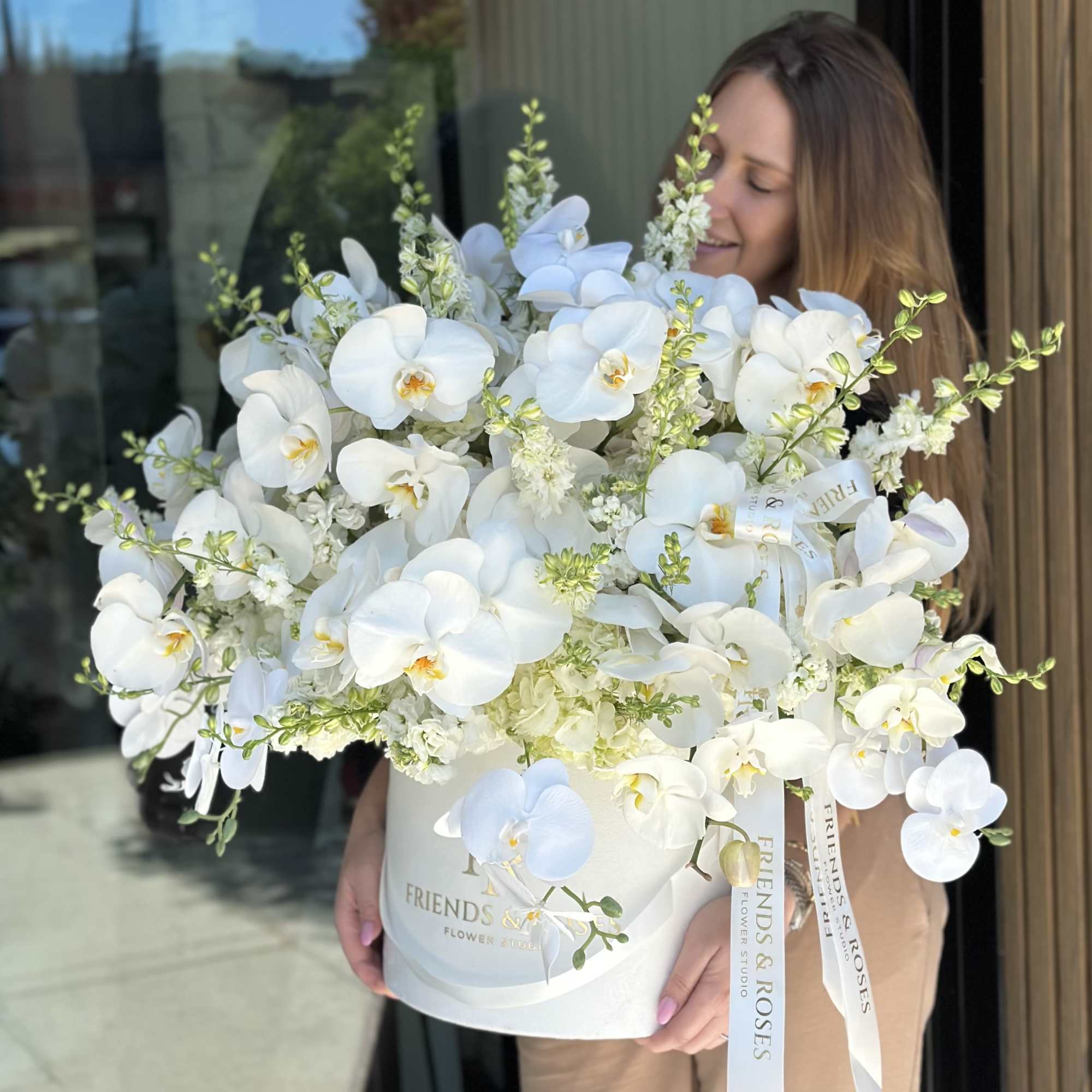 Large white orchid arrangement in a white hatbox