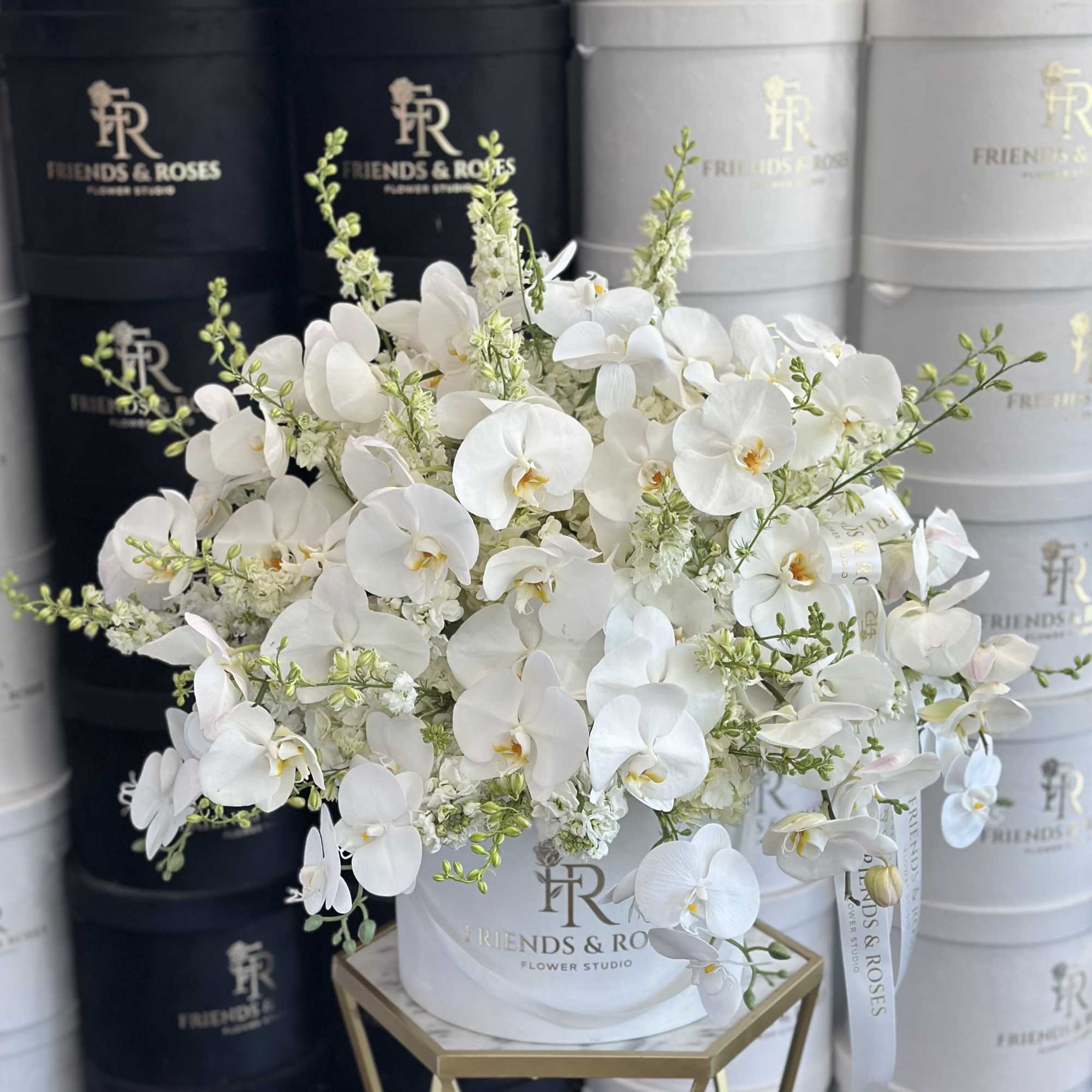 White orchids arranged in a white hat box with a ribbon.