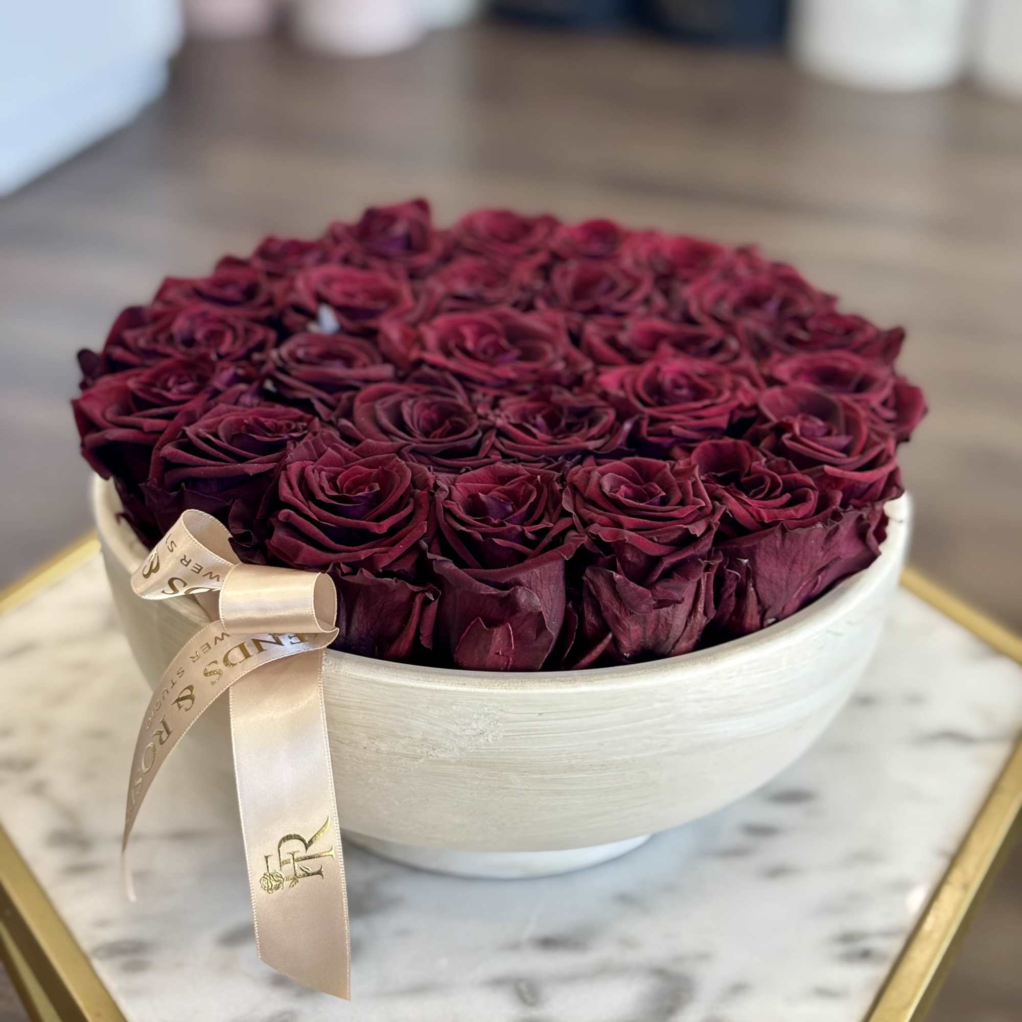 Round box filled with deep red roses and a satin ribbon