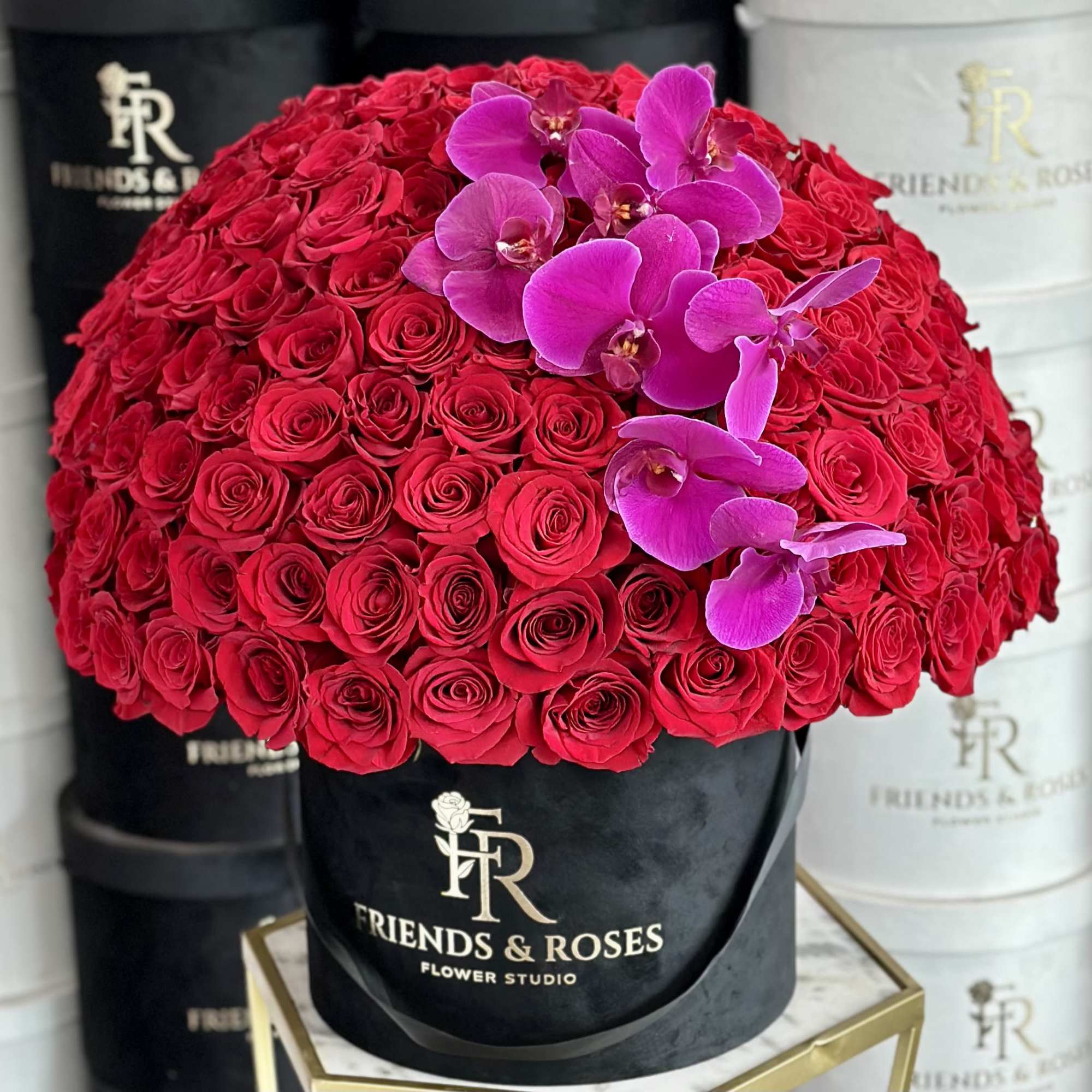 Red rose bouquet with purple orchids in a black hat box