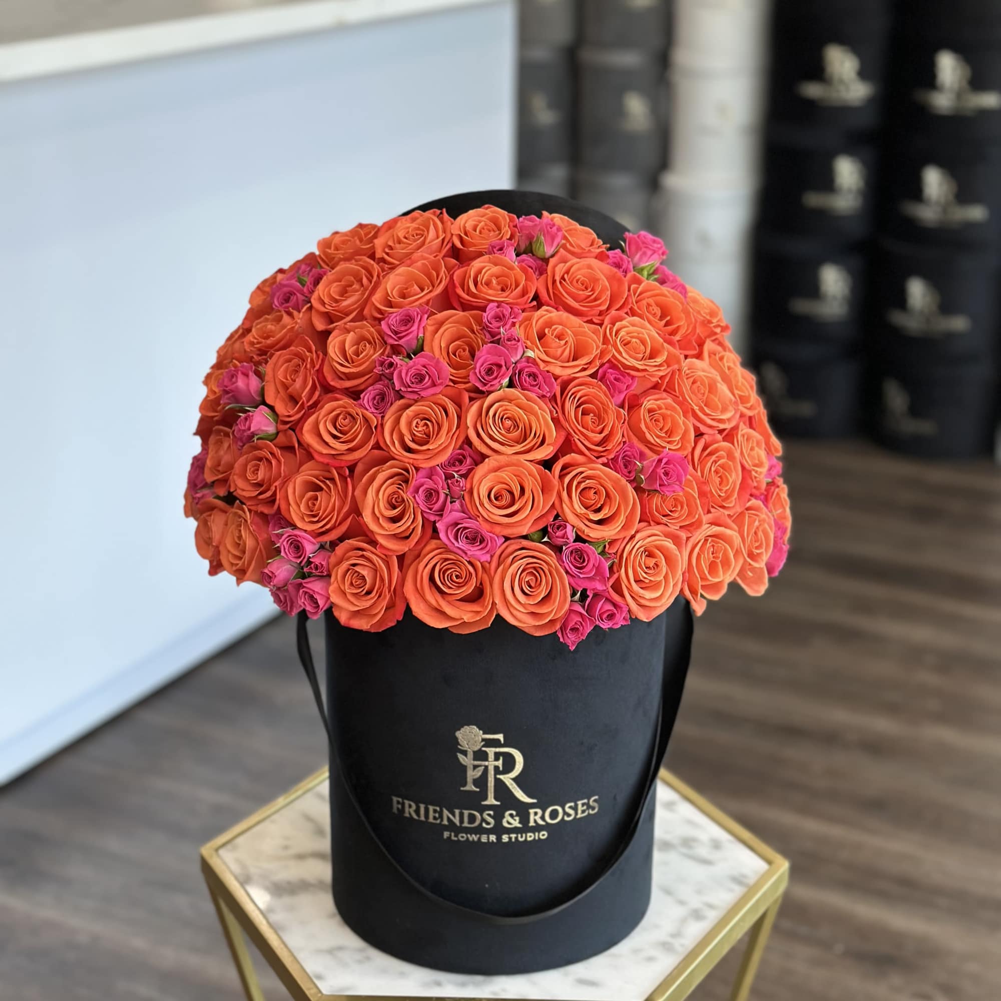Round bouquet of orange and pink roses in a black hat box, photo 2 of 3