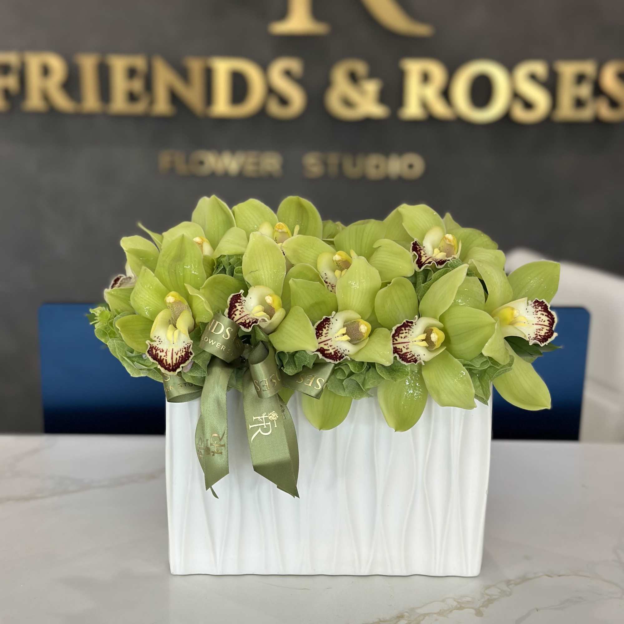 Green orchid arrangement in a white rectangular vase with ribbon, photo 3 of 3