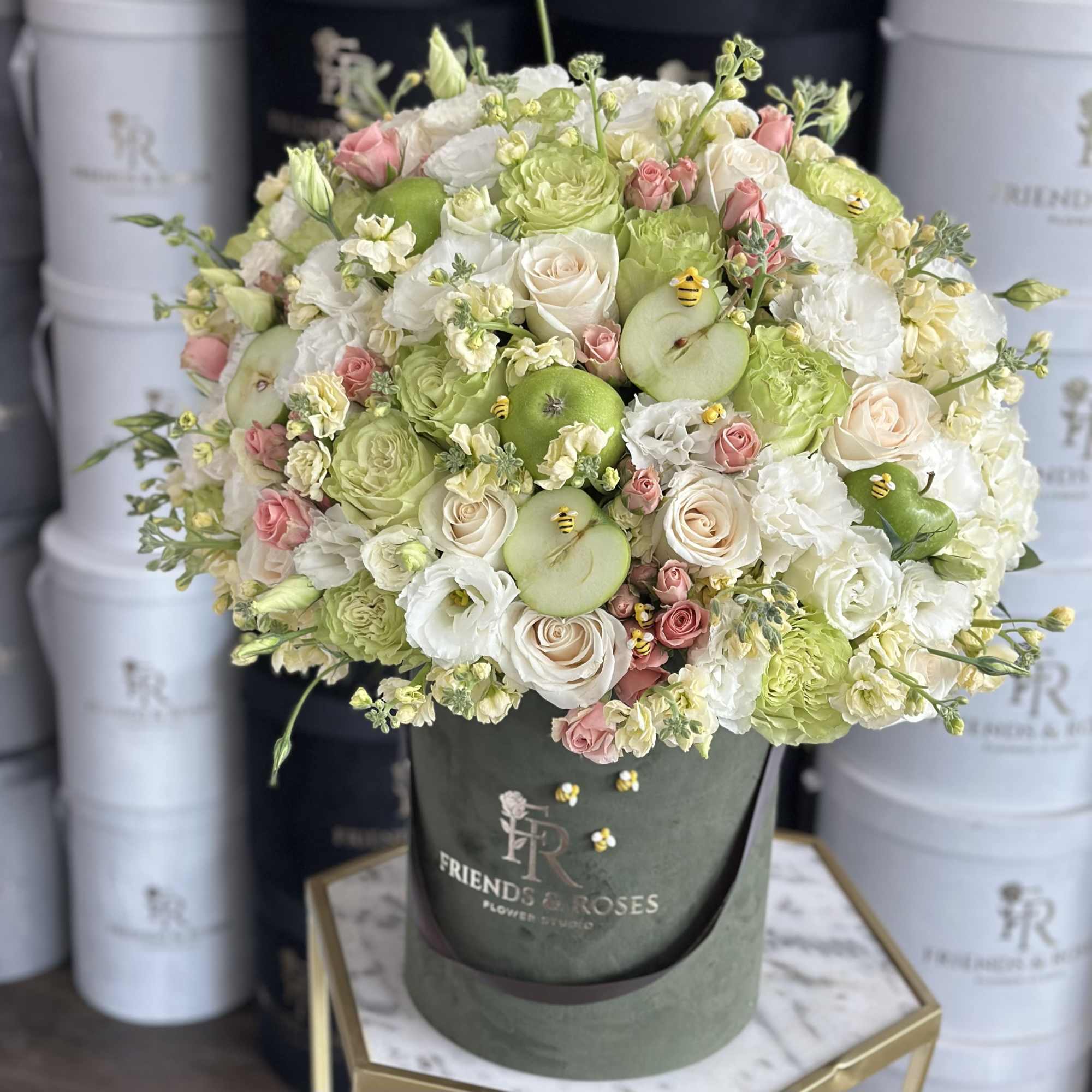 Bouquet of white and blush flowers with green apples in a dark hat box