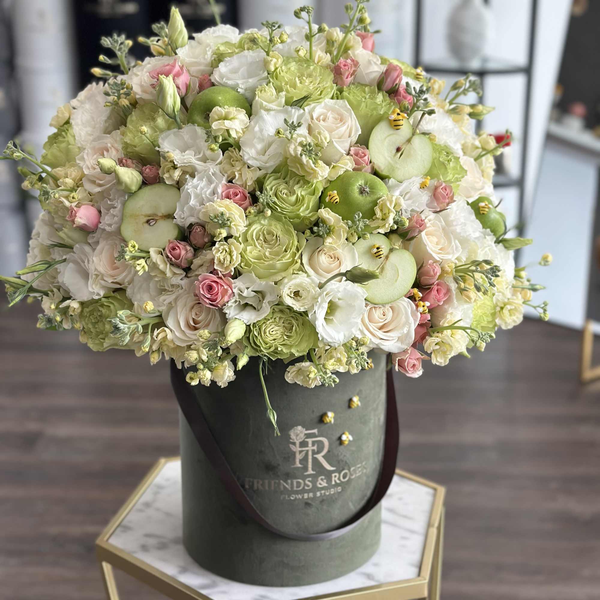Bouquet of white and pink roses with green apples in a dark hatbox