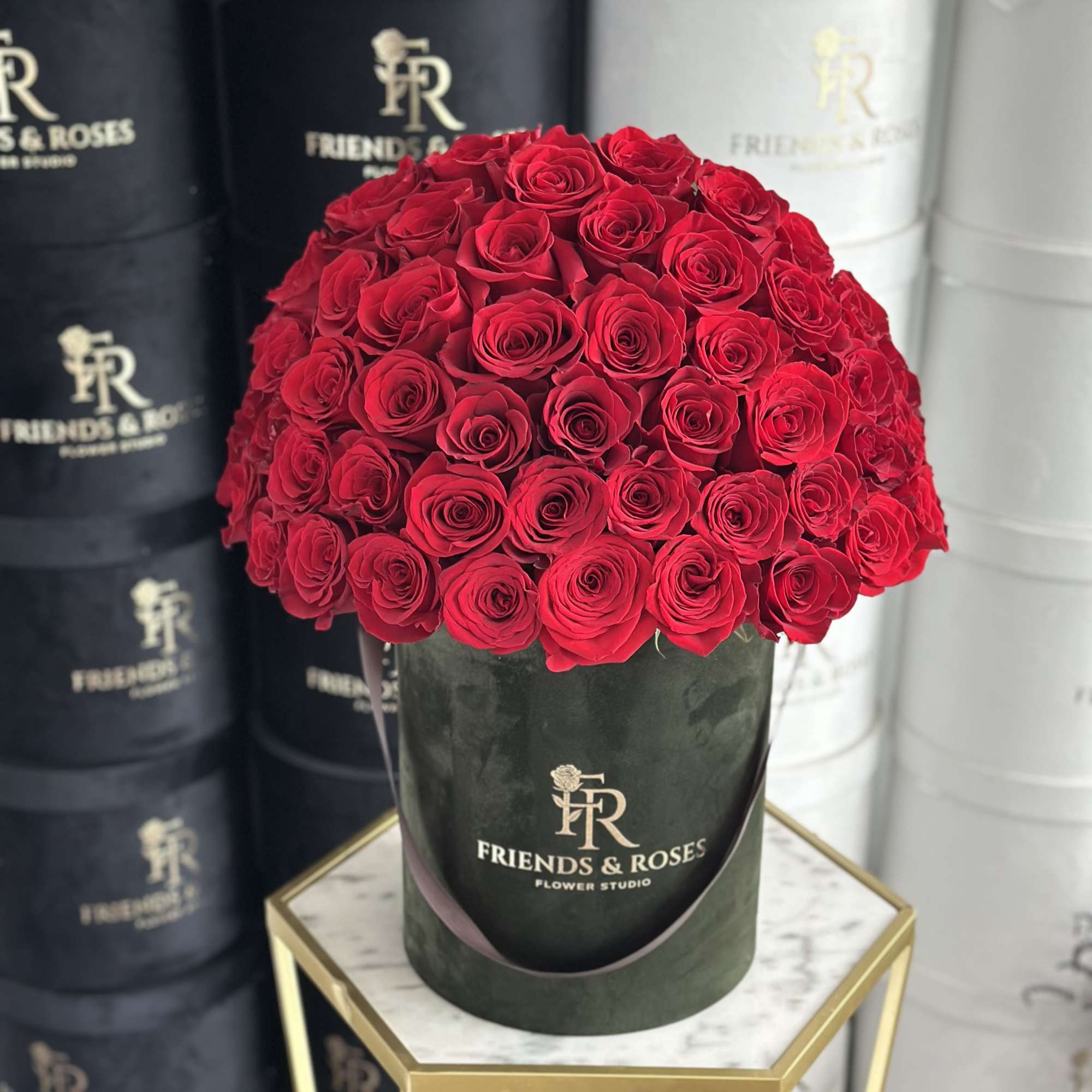 Round bouquet of red roses in a dark green hatbox