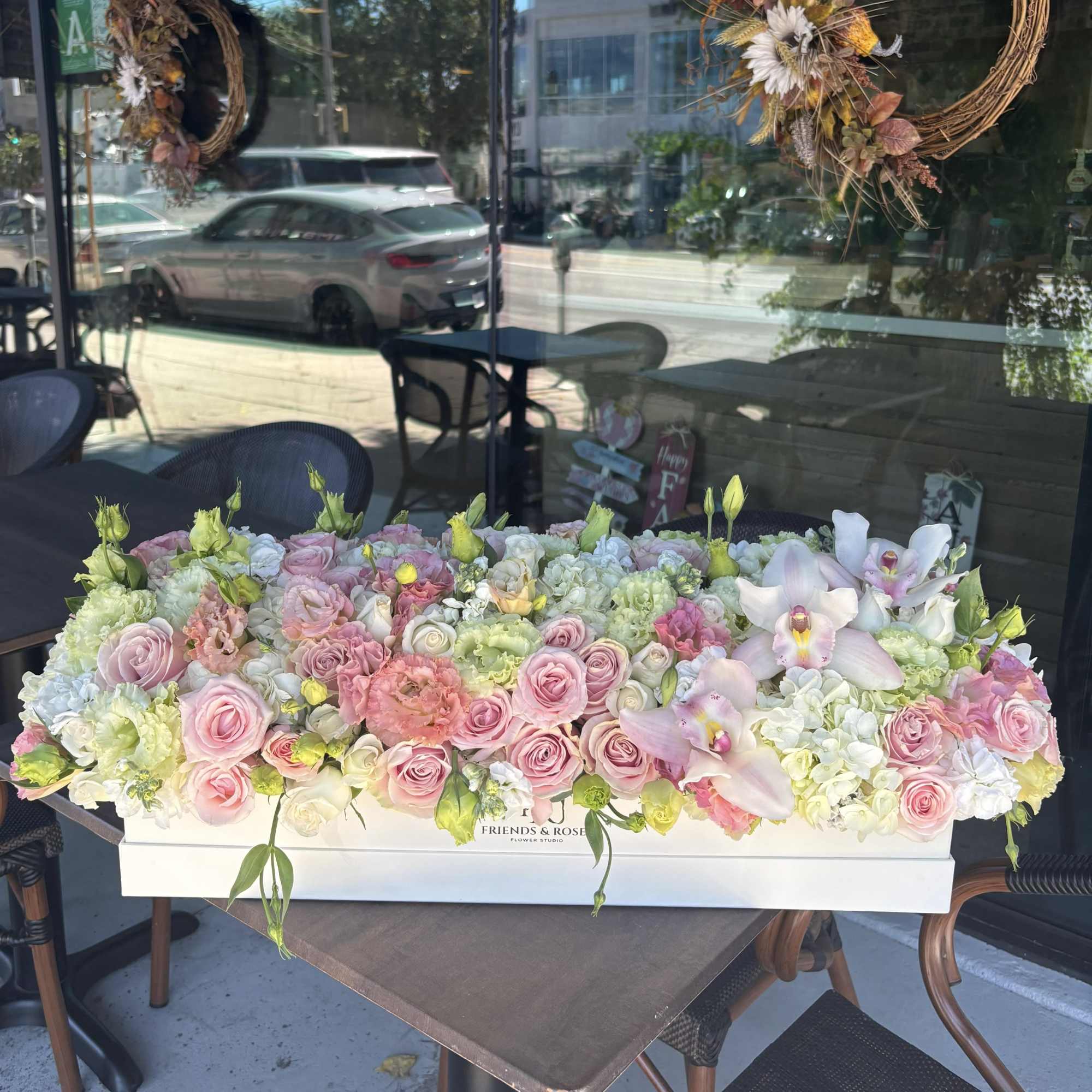Large pastel flower arrangement in a white box with pink roses and orchids