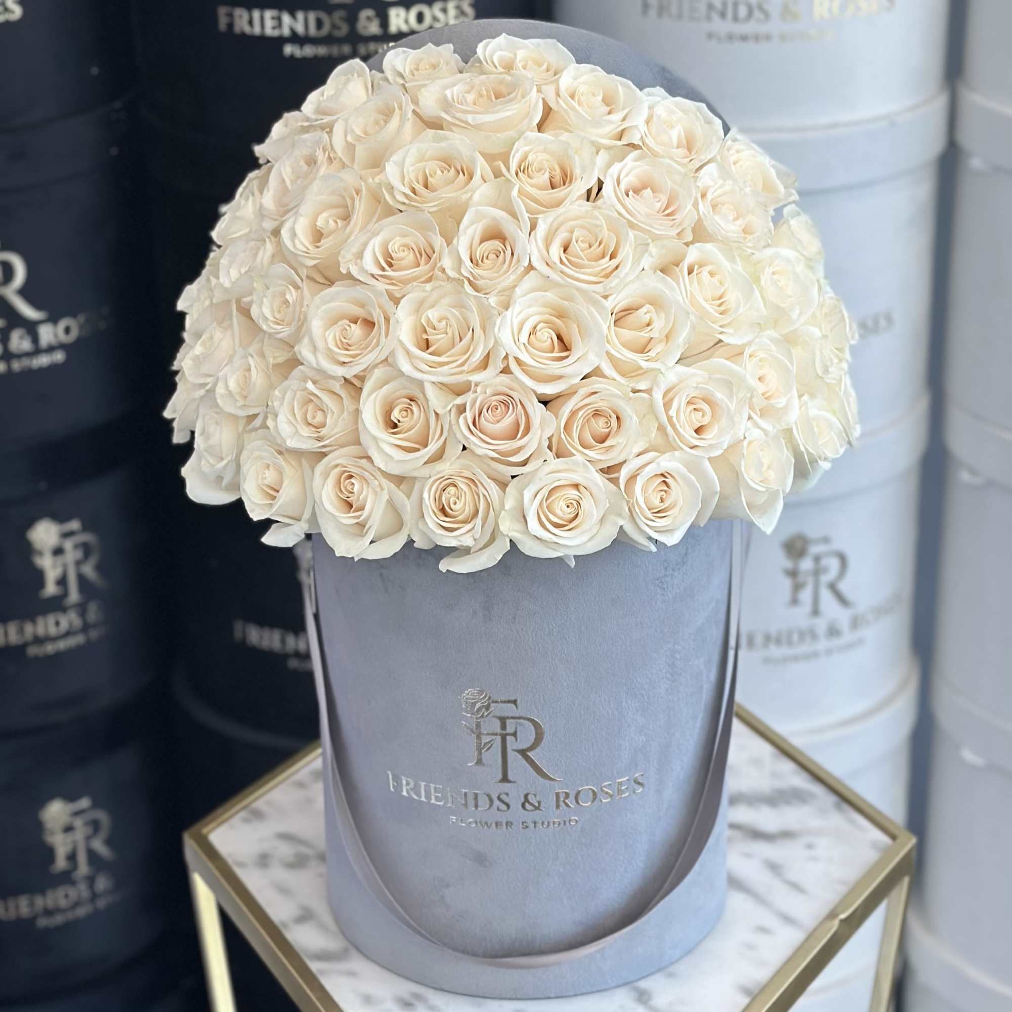 Cream roses arranged in a gray hat box