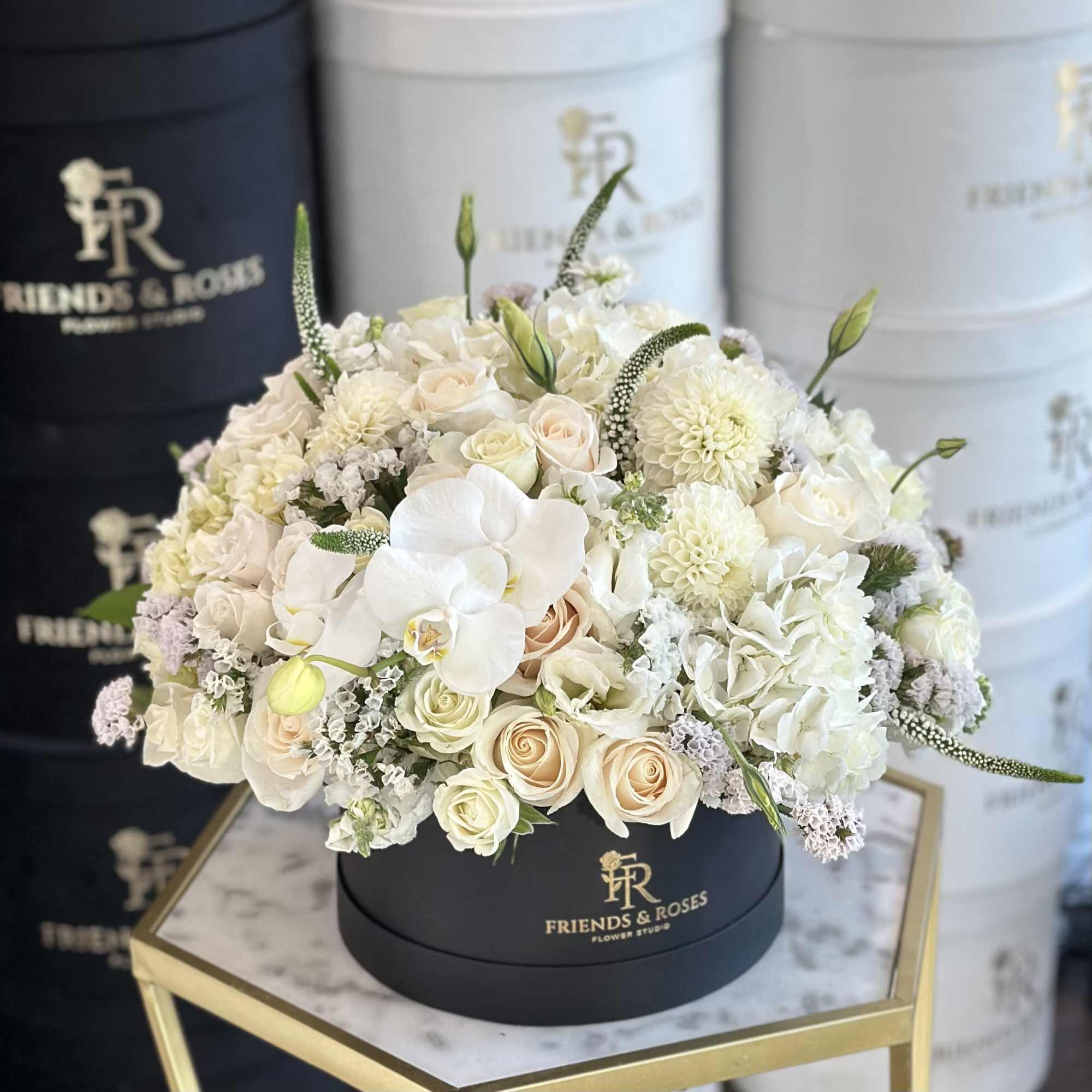 White and blush floral arrangement in a black round box