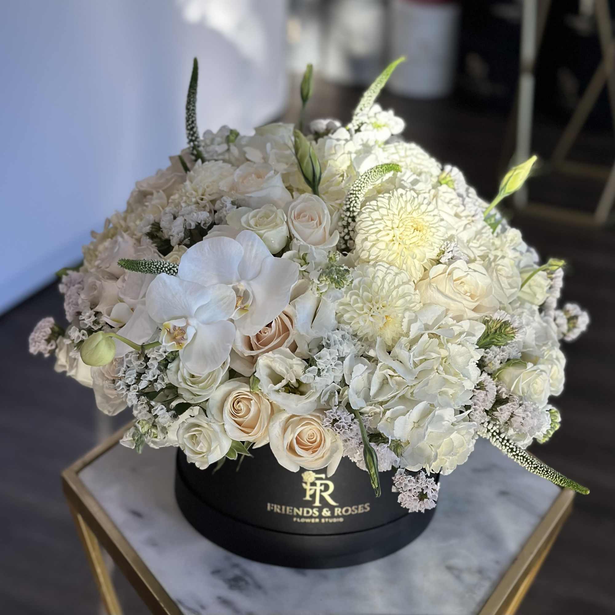 Round white floral arrangement in a black hat box