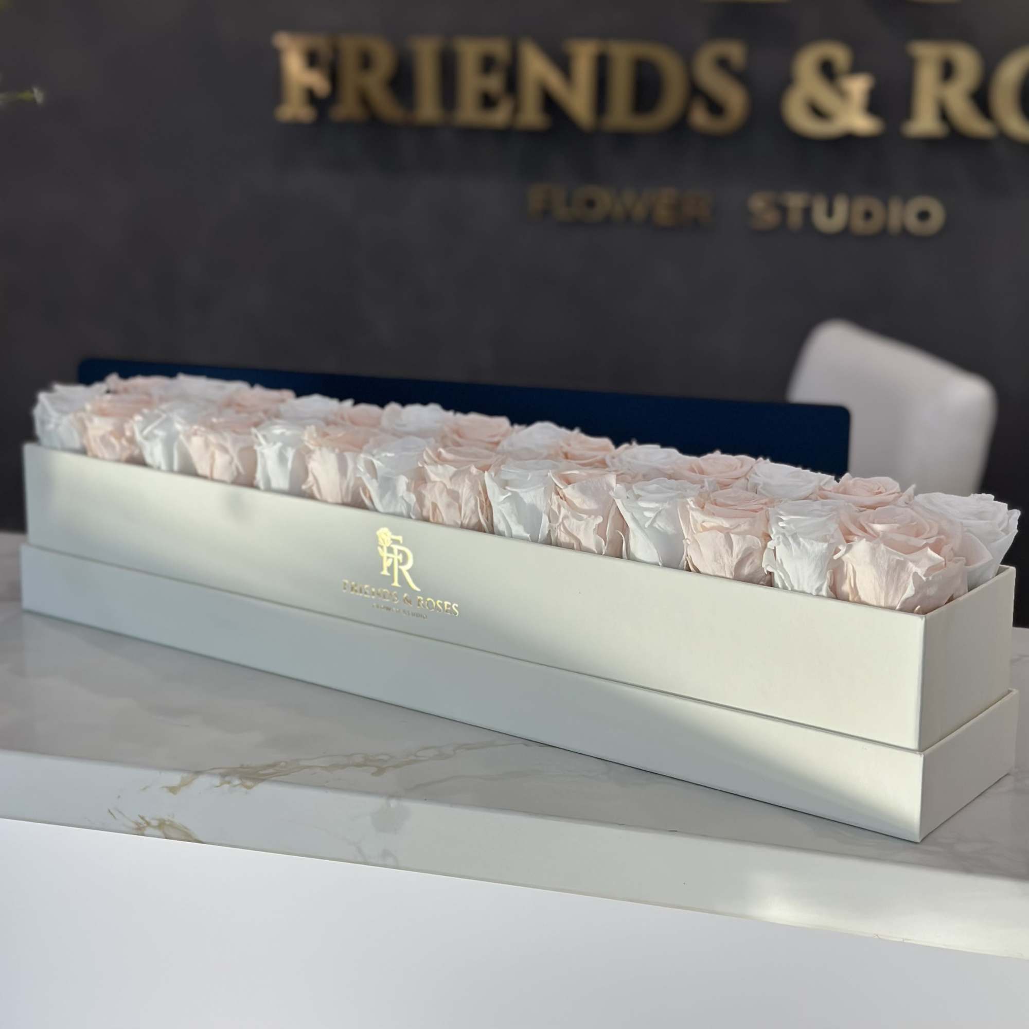 Long box of pale pink and white roses on a table