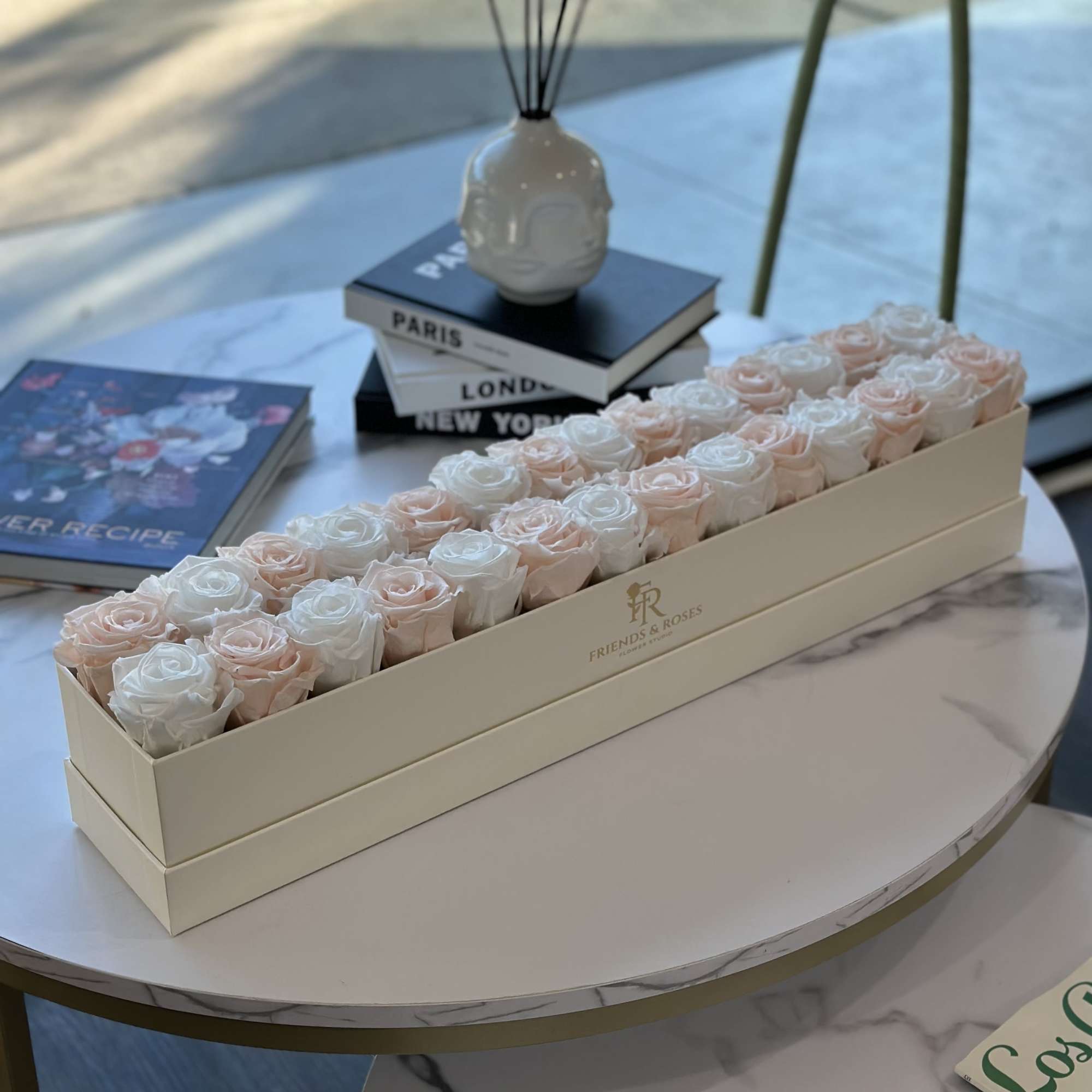 Rectangular box of pale pink and white roses on a round table