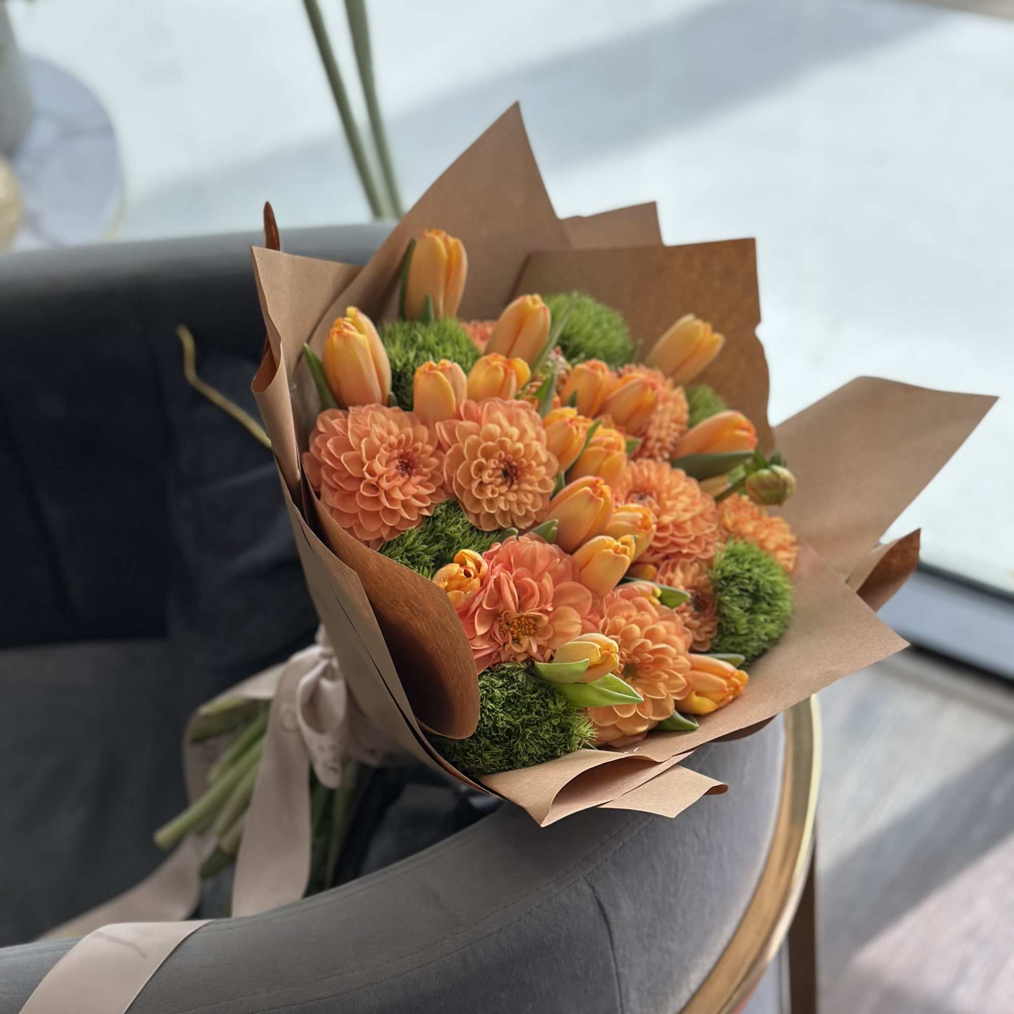 Orange flowers wrapped in brown paper with a ribbon
