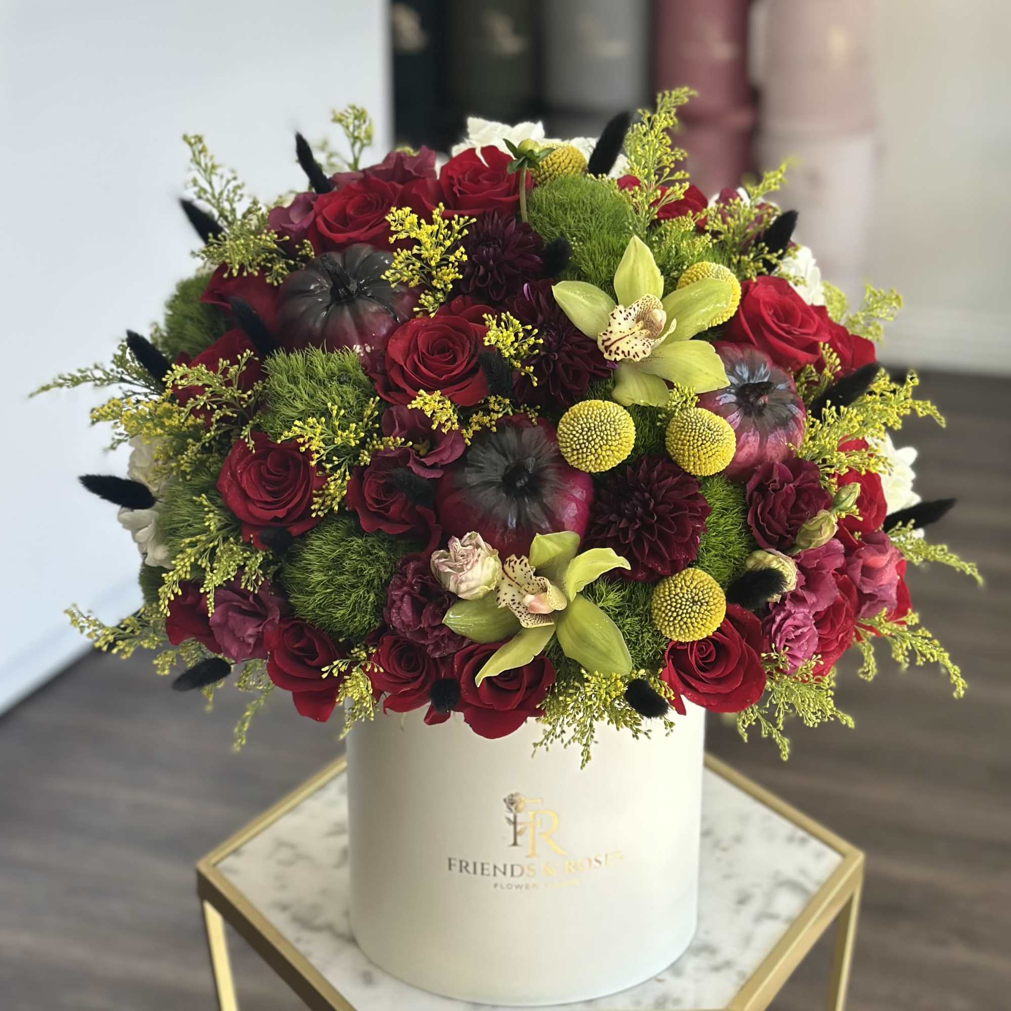 Red roses and mixed blooms arranged in a white hat box
