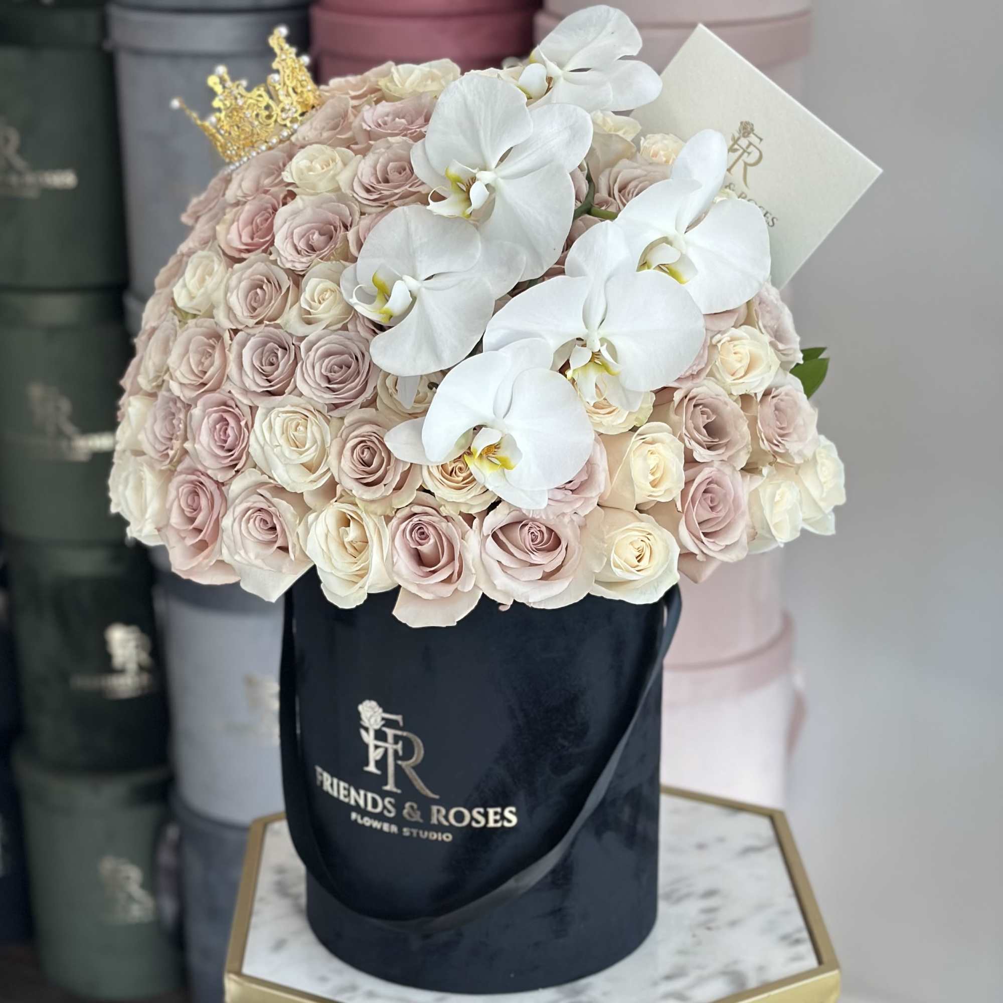 Round bouquet of pale pink and cream roses with white orchids in a black hat box