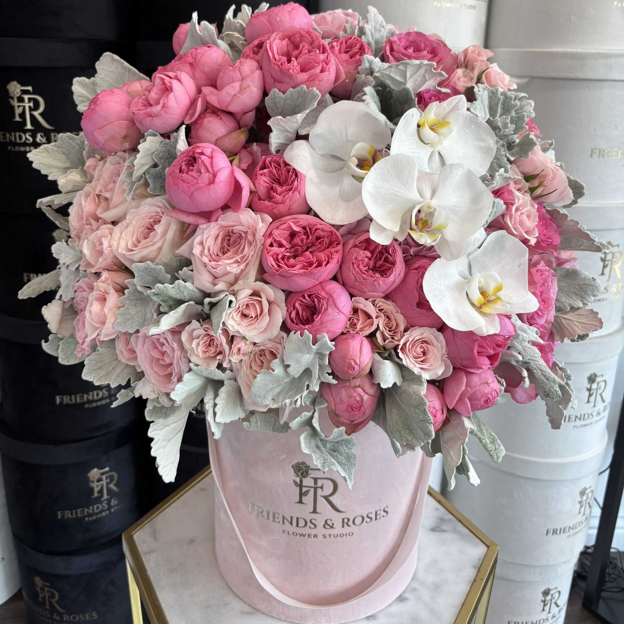 Pink roses and white orchids in a pink hat box